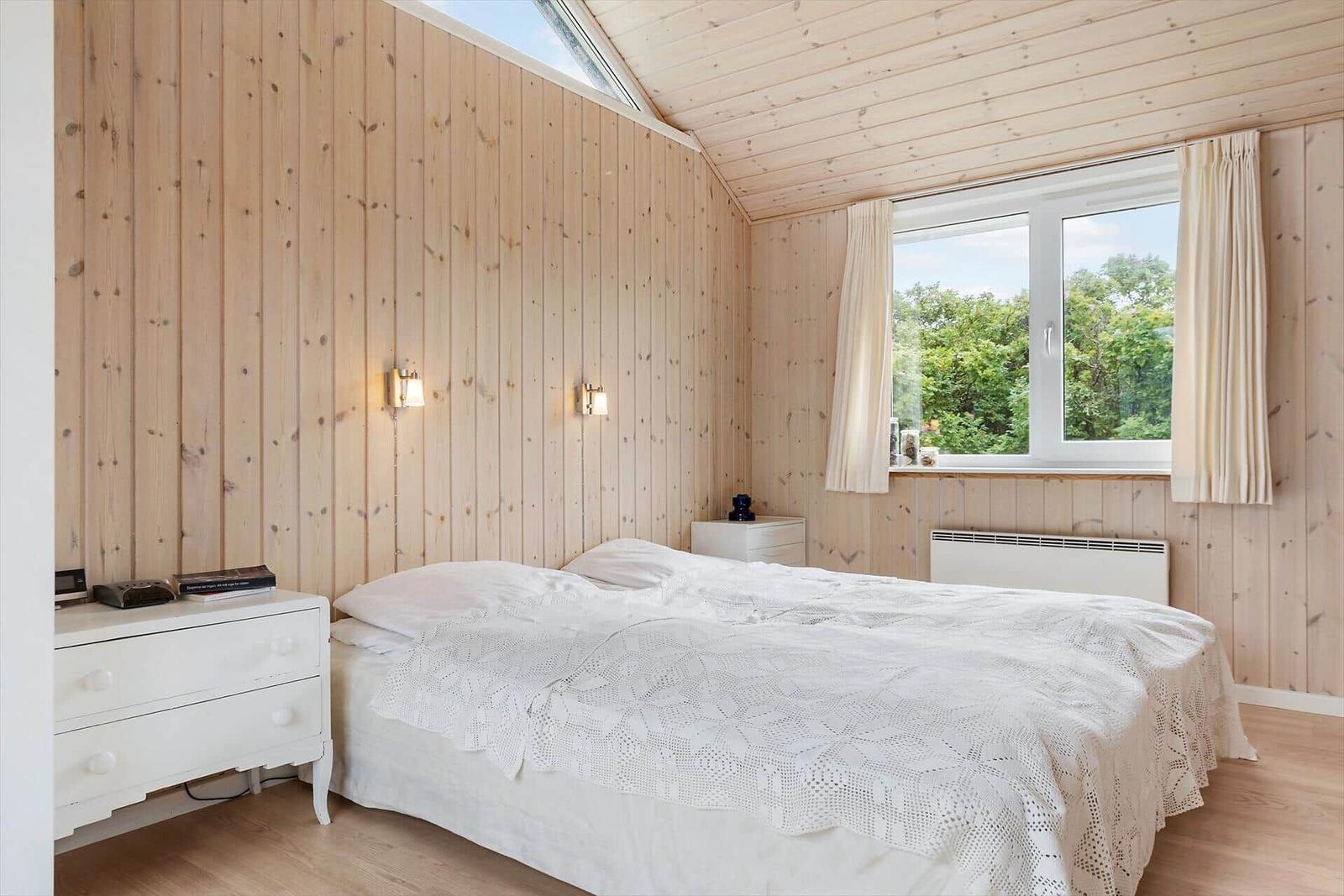 Badezimmer mit Dusche, Toilette und Waschbecken. Holzdecke und Fliesenboden.