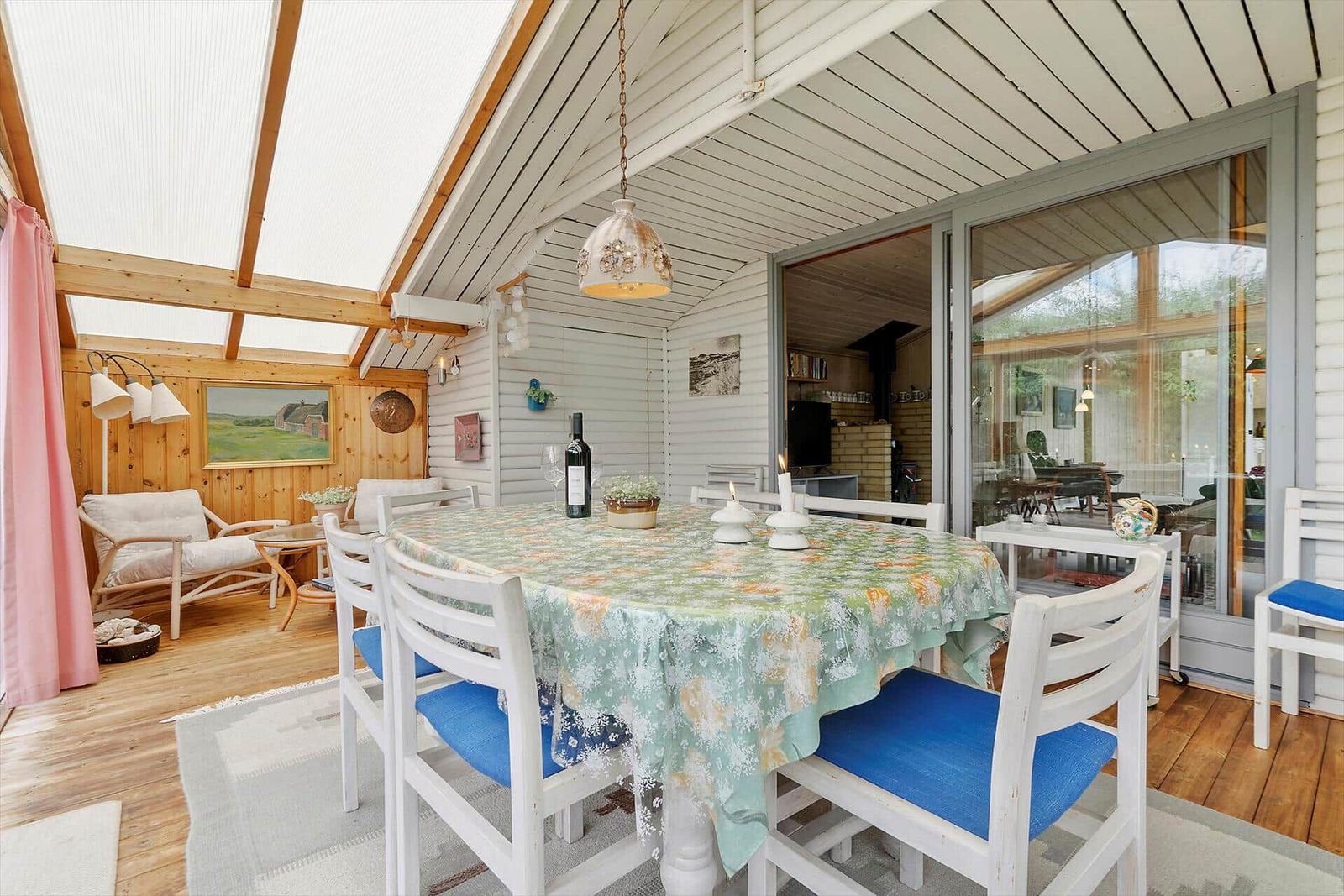 Terrasse mit grüner Liege und Blick in das Haus mit Essbereich.