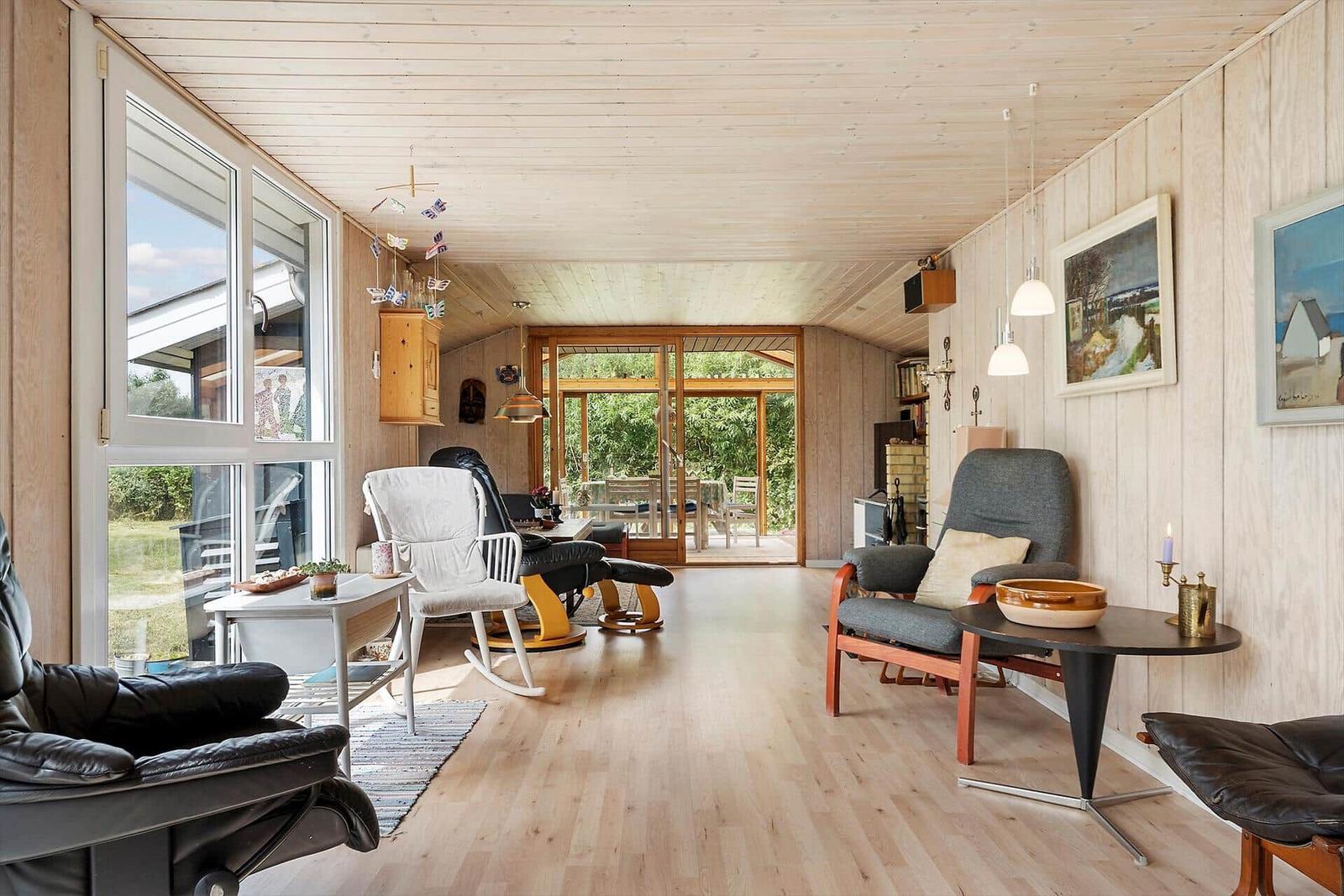 Wohnzimmer mit grauem Sofa, Holztisch und Fenster mit Blick auf Grün.