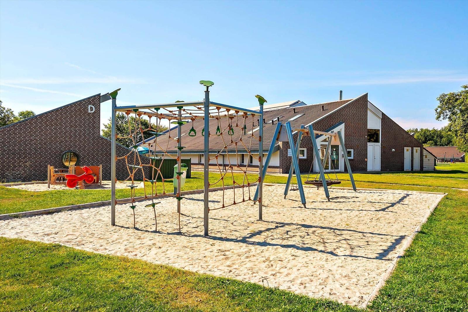 Kinderbereich mit Sandkasten und Klettergerüst vor Gebäude