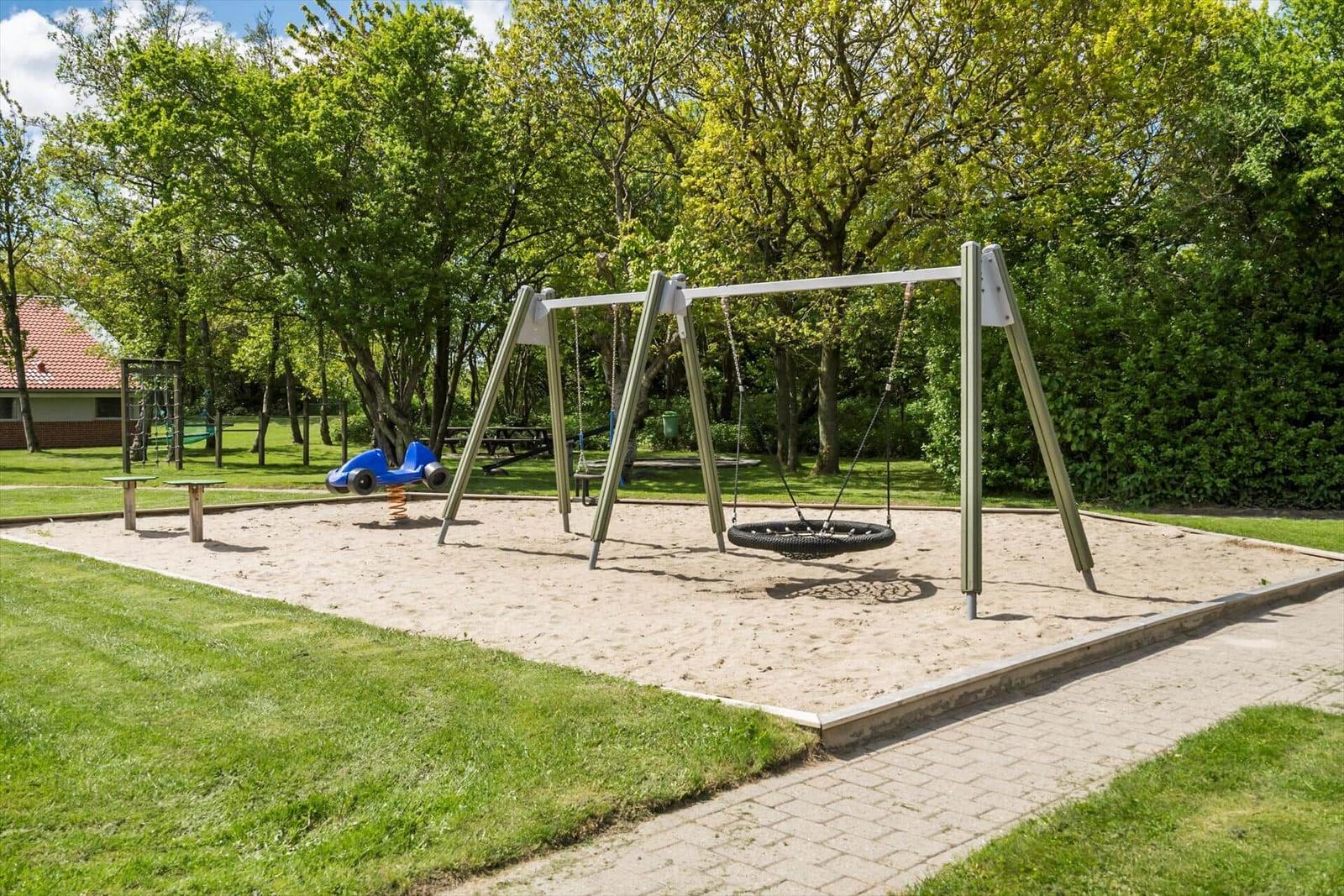 Kinderbereich mit Sandkasten, Schaukel und Spielzeugauto im Grünbereich