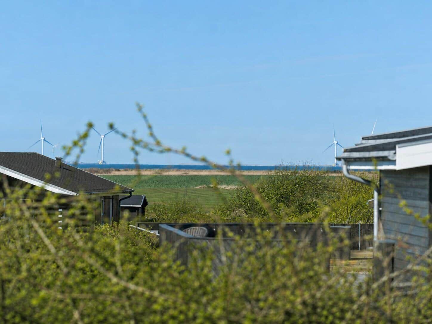 Terrasse mit Sitzgruppe, Liegestühlen und Beleuchtung. Blick auf Wohngebiet mit dänischer Flagge.