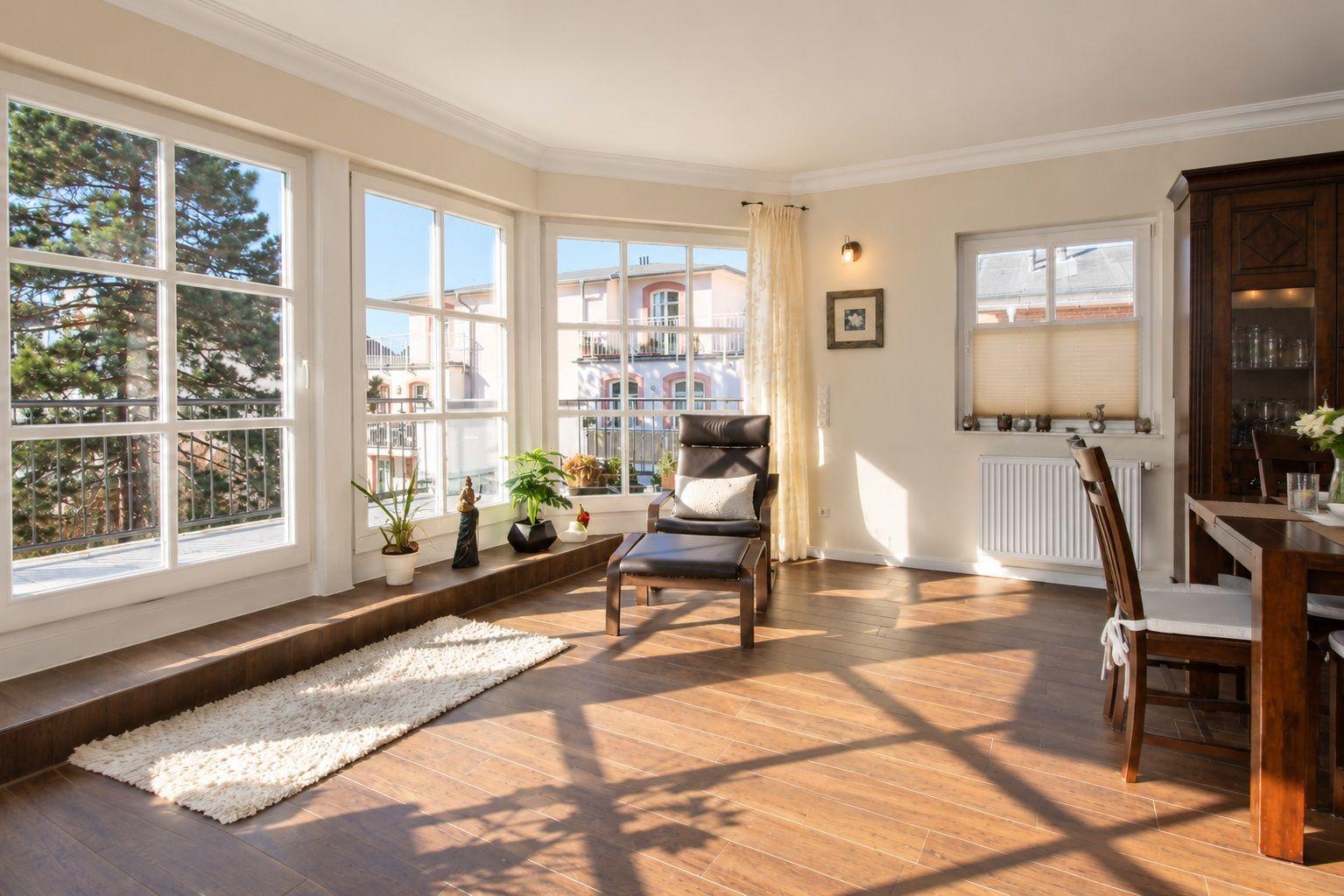 Großes Wohnzimmer mit viel Licht und Blick auf Balkon und Baum.