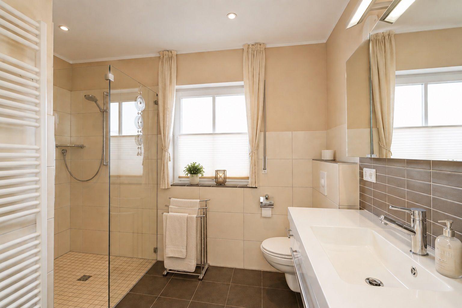 Badezimmer mit Dusche, Waschbecken und Toilette. Fenster mit Vorhängen.