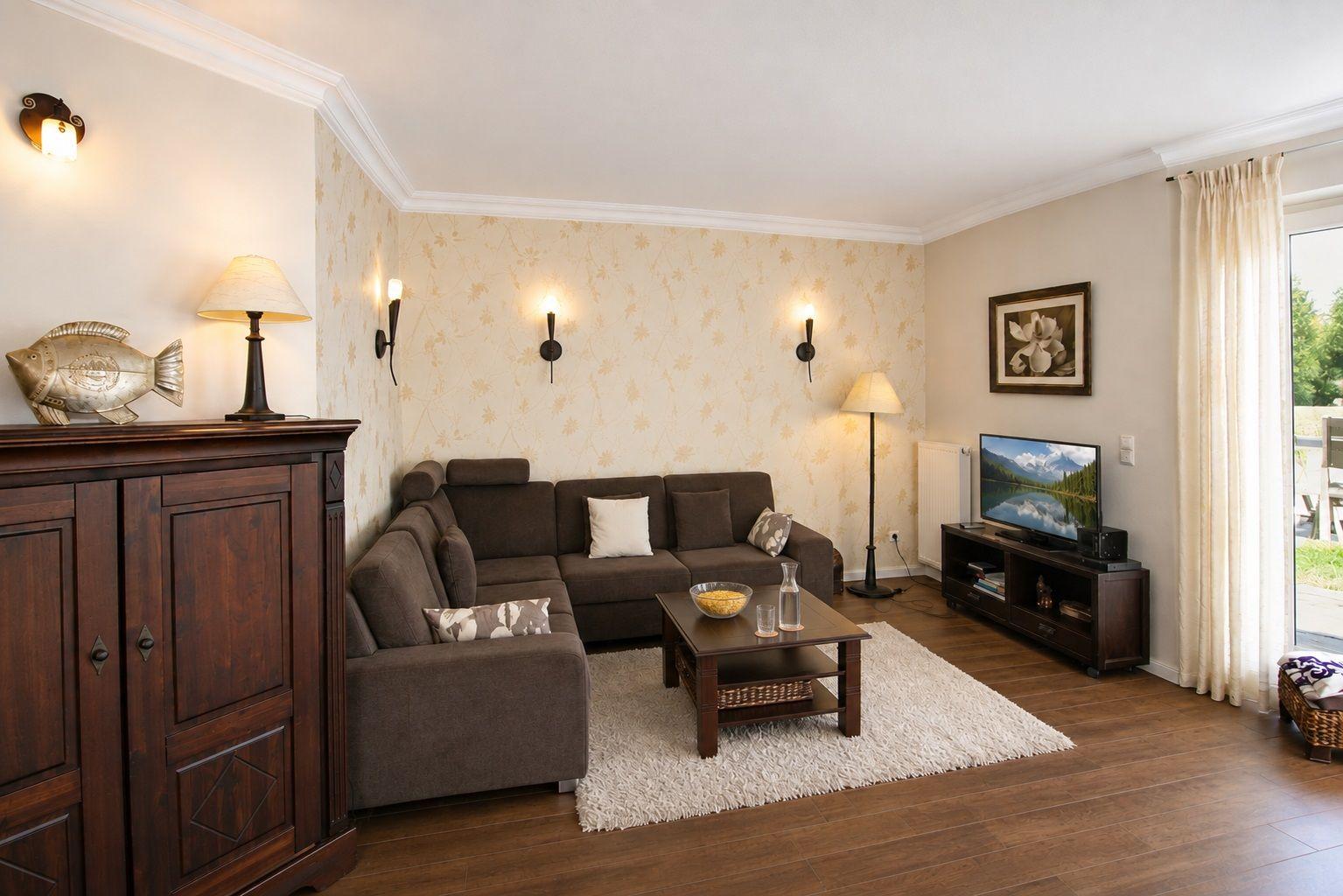 Wohnzimmer mit Sofa, Couchtisch und Fernseher. Holzboden und Wandbehang.