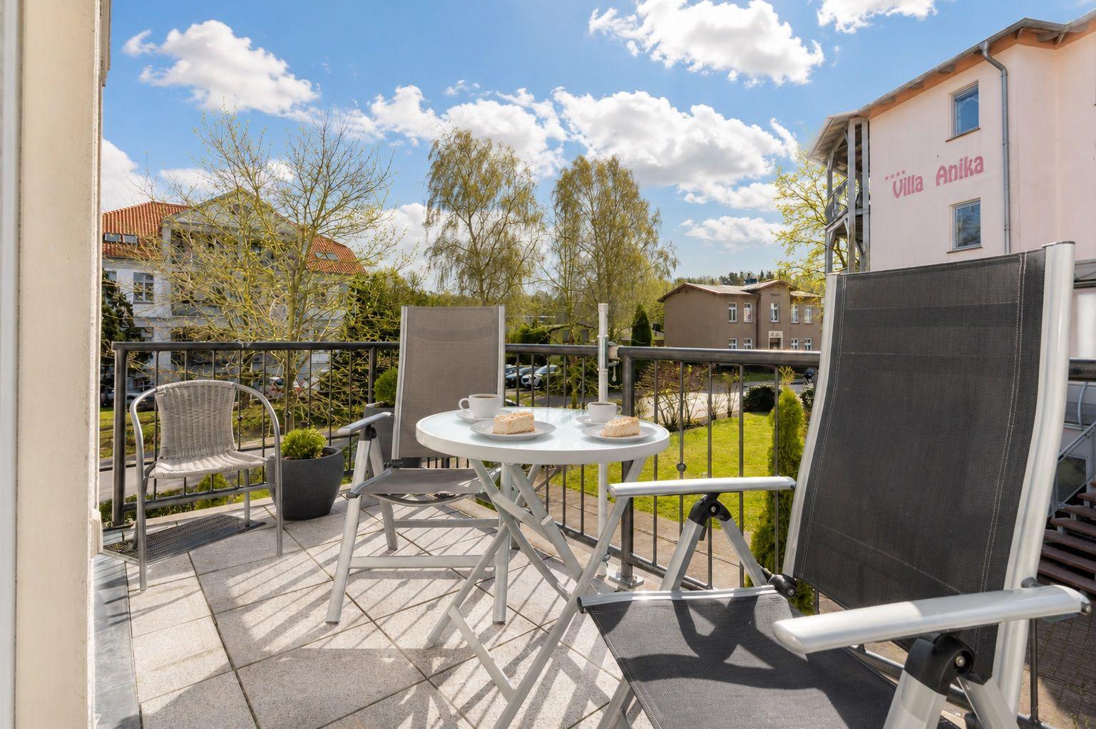 Hausflur mit Blick in Wohnbereich und Balkon mit Stühlen.