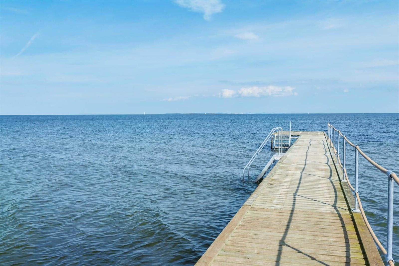Rettungsring an Pfosten am Strand mit Blick auf Meer und Himmel.
