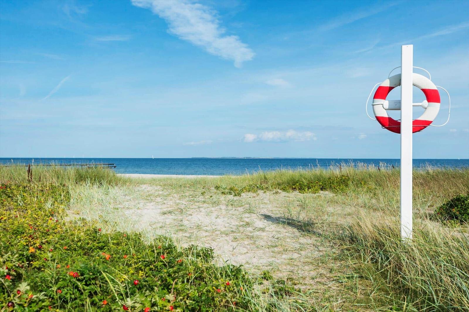 Strand mit Sand und einem blauen Boot am Wasser.