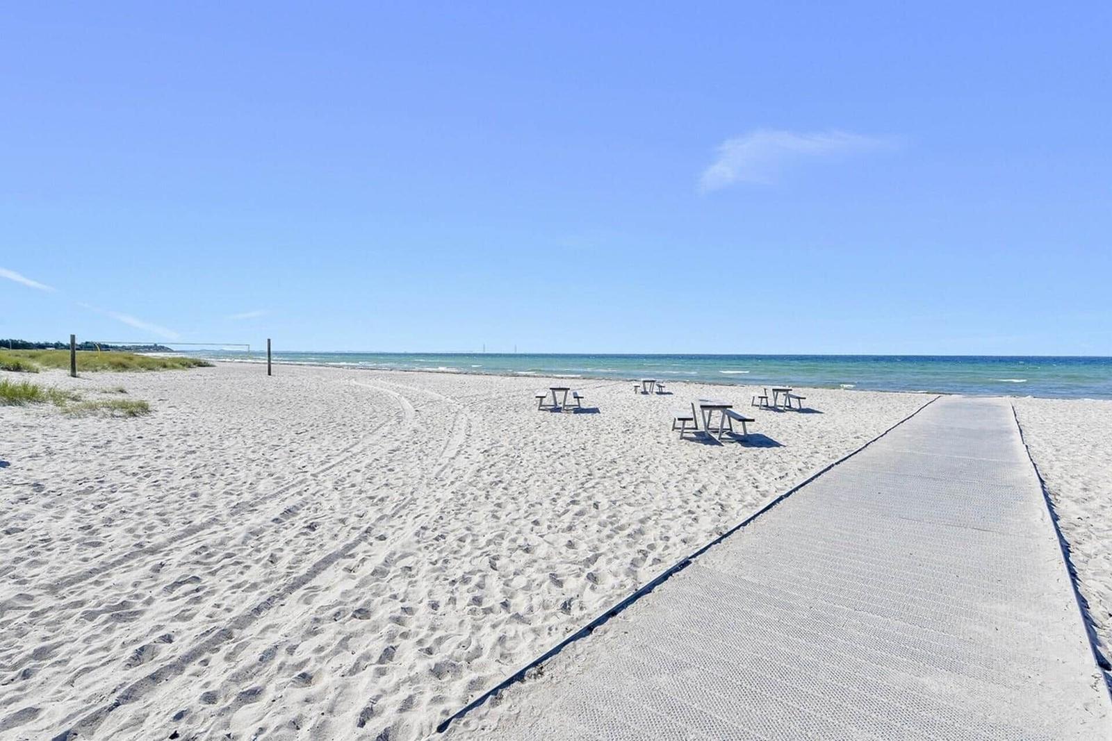 Strand mit Menschen, See und Brücke im Hintergrund