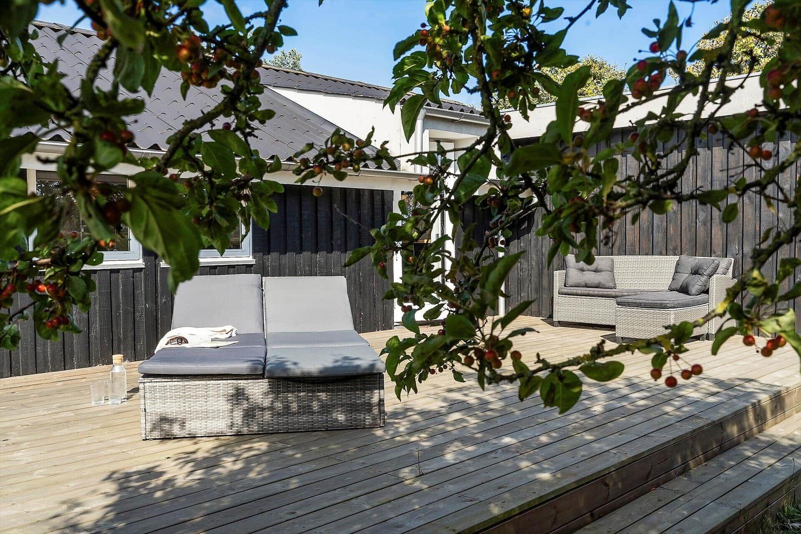 Deck with table, chairs, and grill. Access to living area. Backyard with greenery.