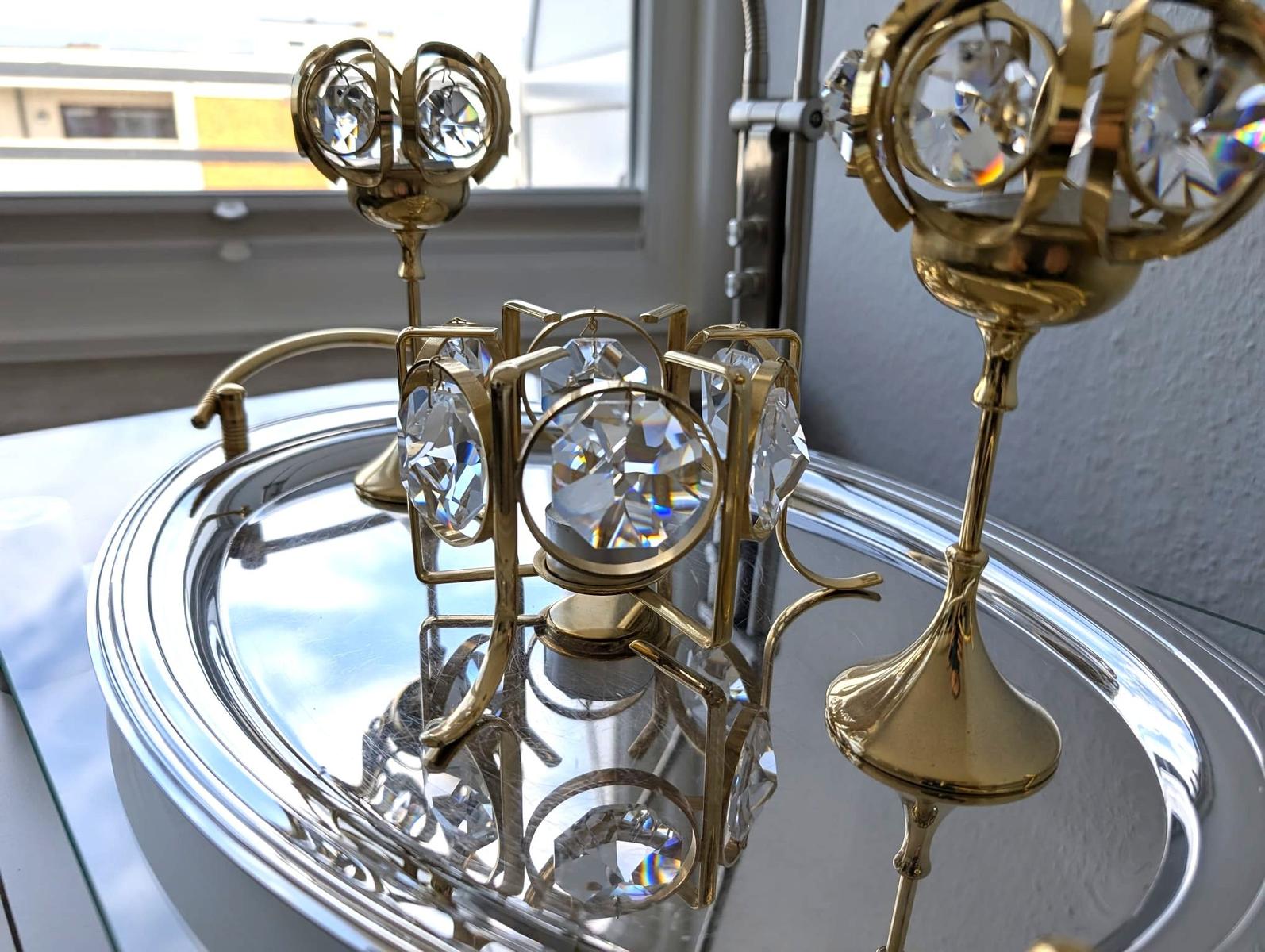 Goldene Kerzenhalter mit Glaskristallen auf ovalem silbernem Tablett.