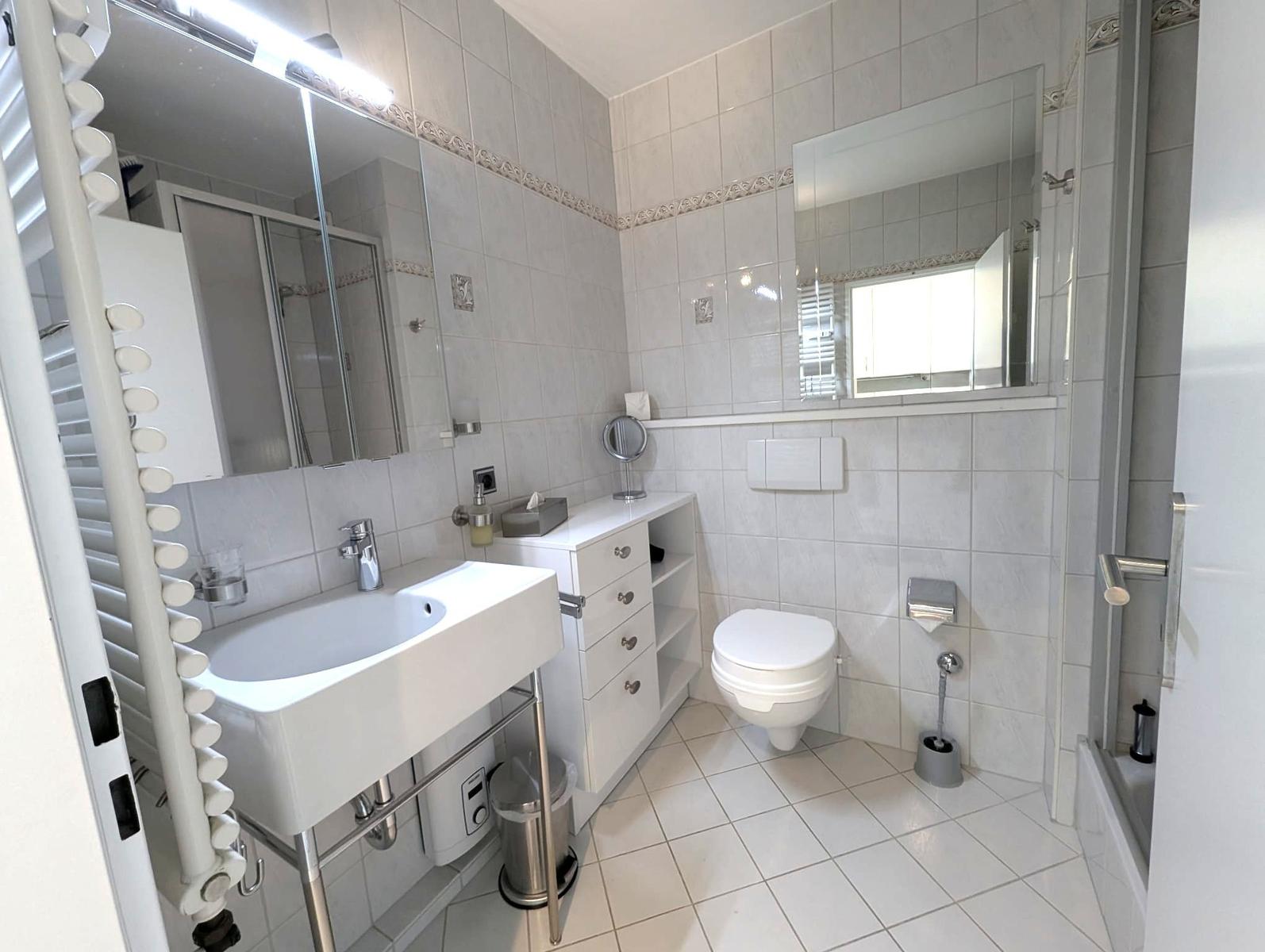 Badezimmer mit Waschbecken, Spiegelschrank, WC und weißem Schrank.