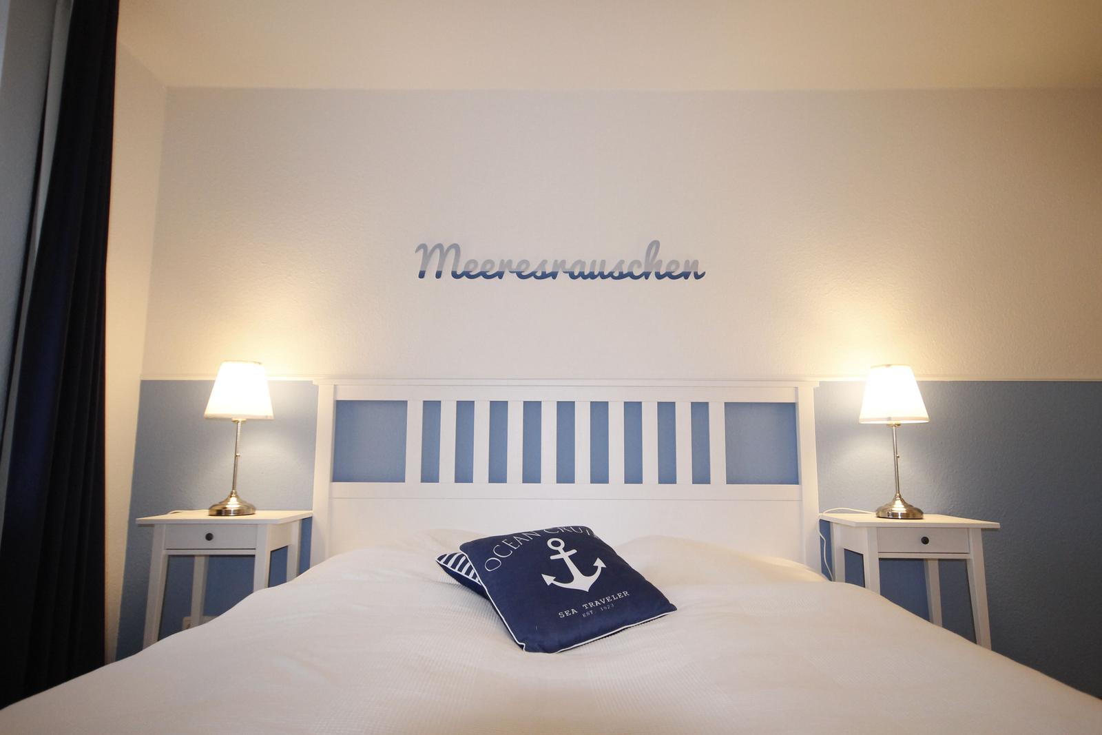 Schlafzimmer mit Bett, zwei Nachttischen und Wanddekoration.