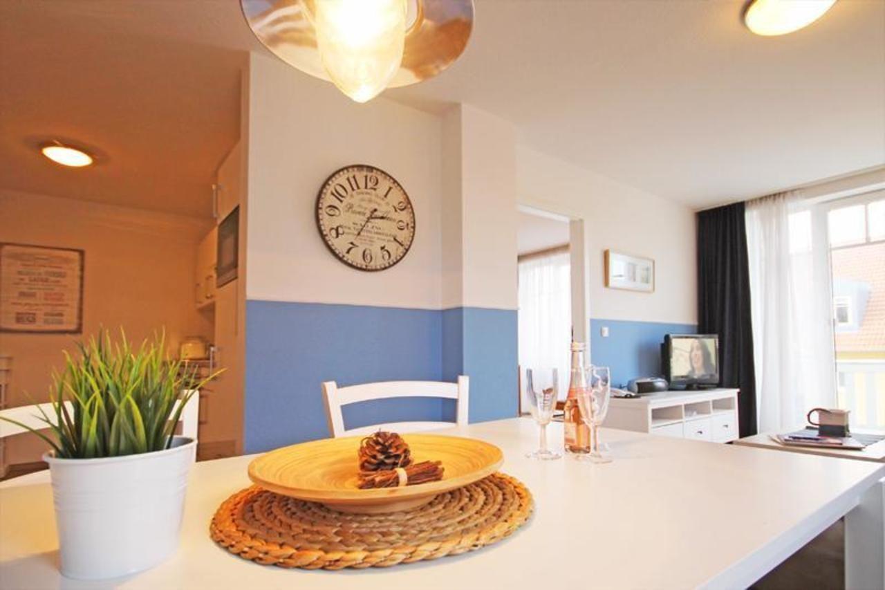 Essbereich mit Tisch, Stuhl und Wanduhr. Küche und Wohnzimmer im Hintergrund.