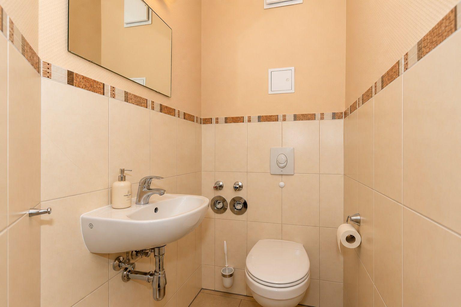 Badezimmer mit Waschbecken, Toilette und Spiegel an der Wand.