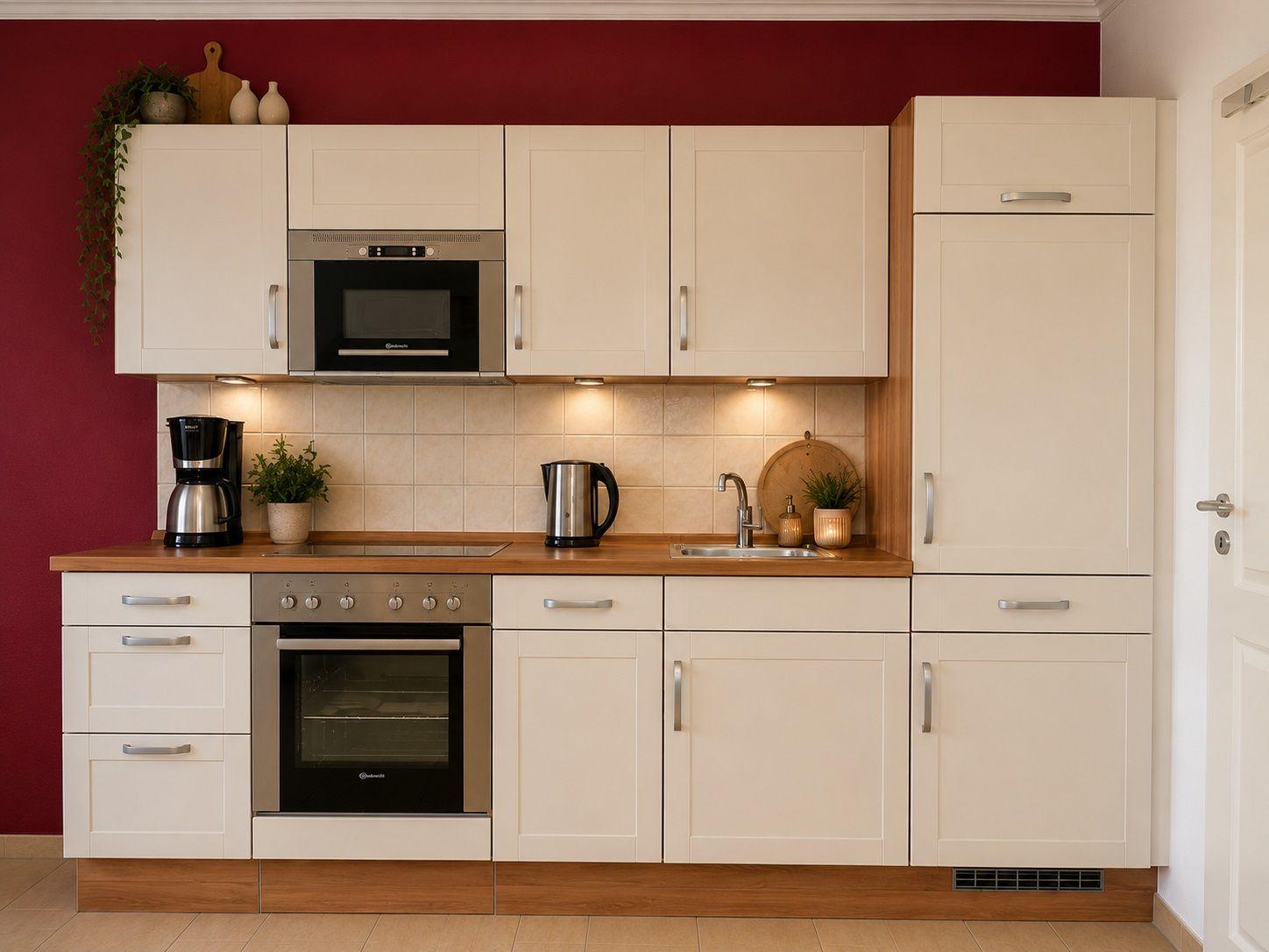 Küche mit weißen Schränken, Edelstahlgeräten und Holz Arbeitsplatte.