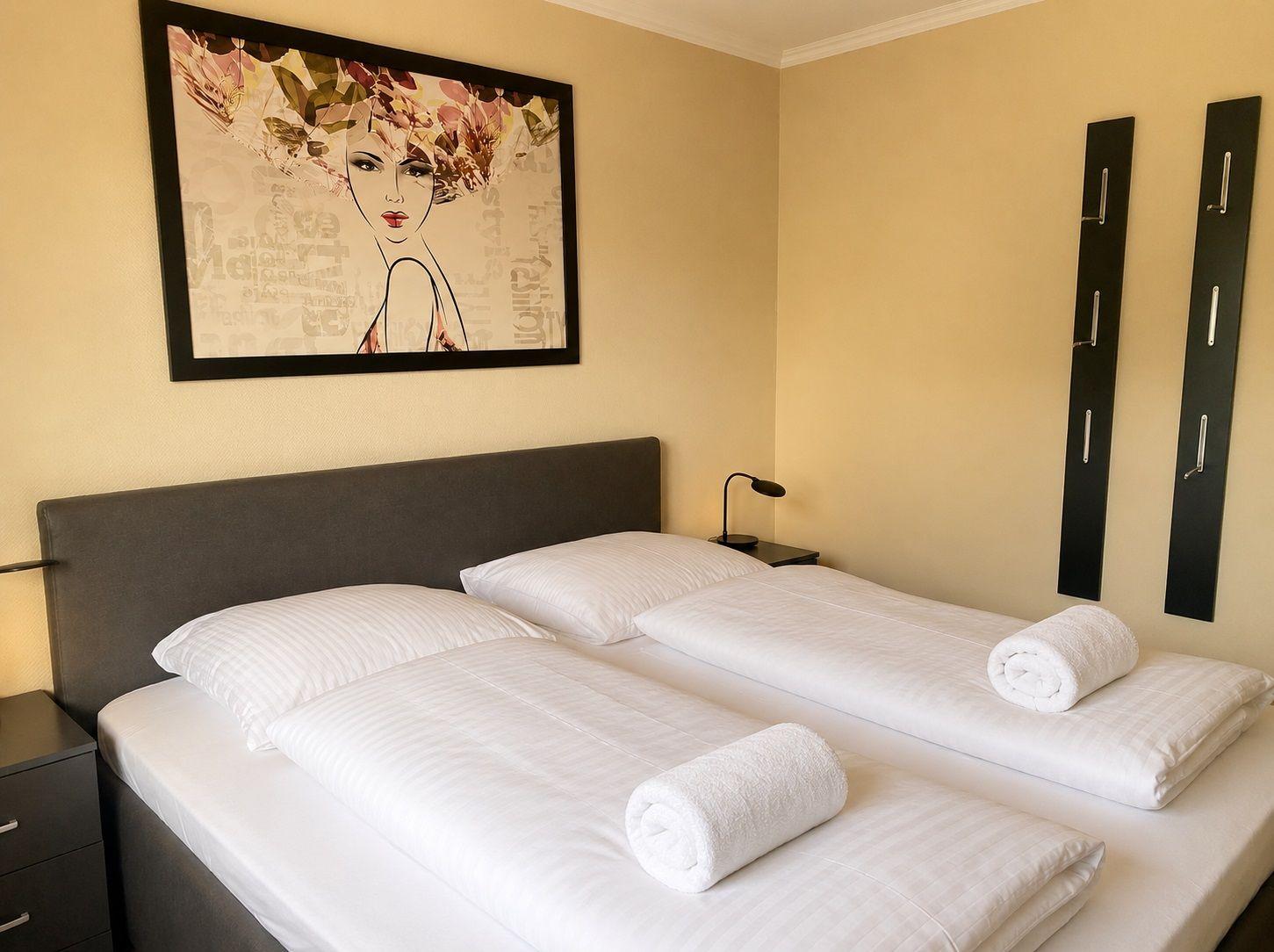 Schlafzimmer mit Doppelbett, Bettwäsche und Wandbild.