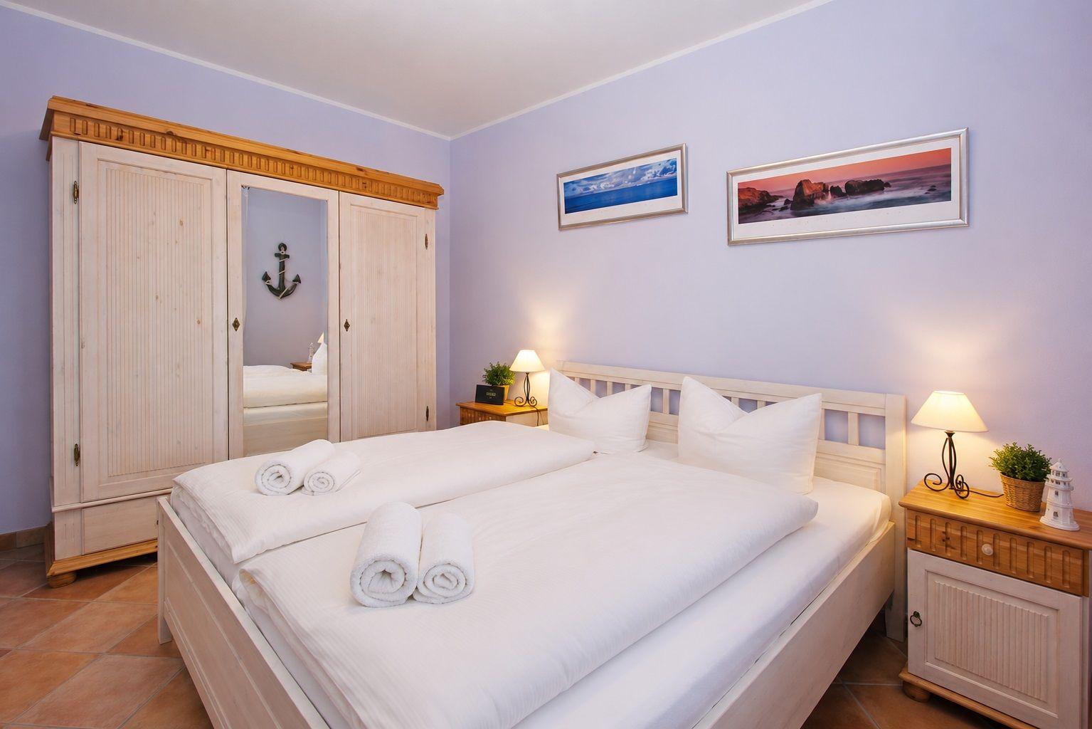 Schlafzimmer mit Doppelbett, Kleiderschrank und Nachttischen mit Lampen.