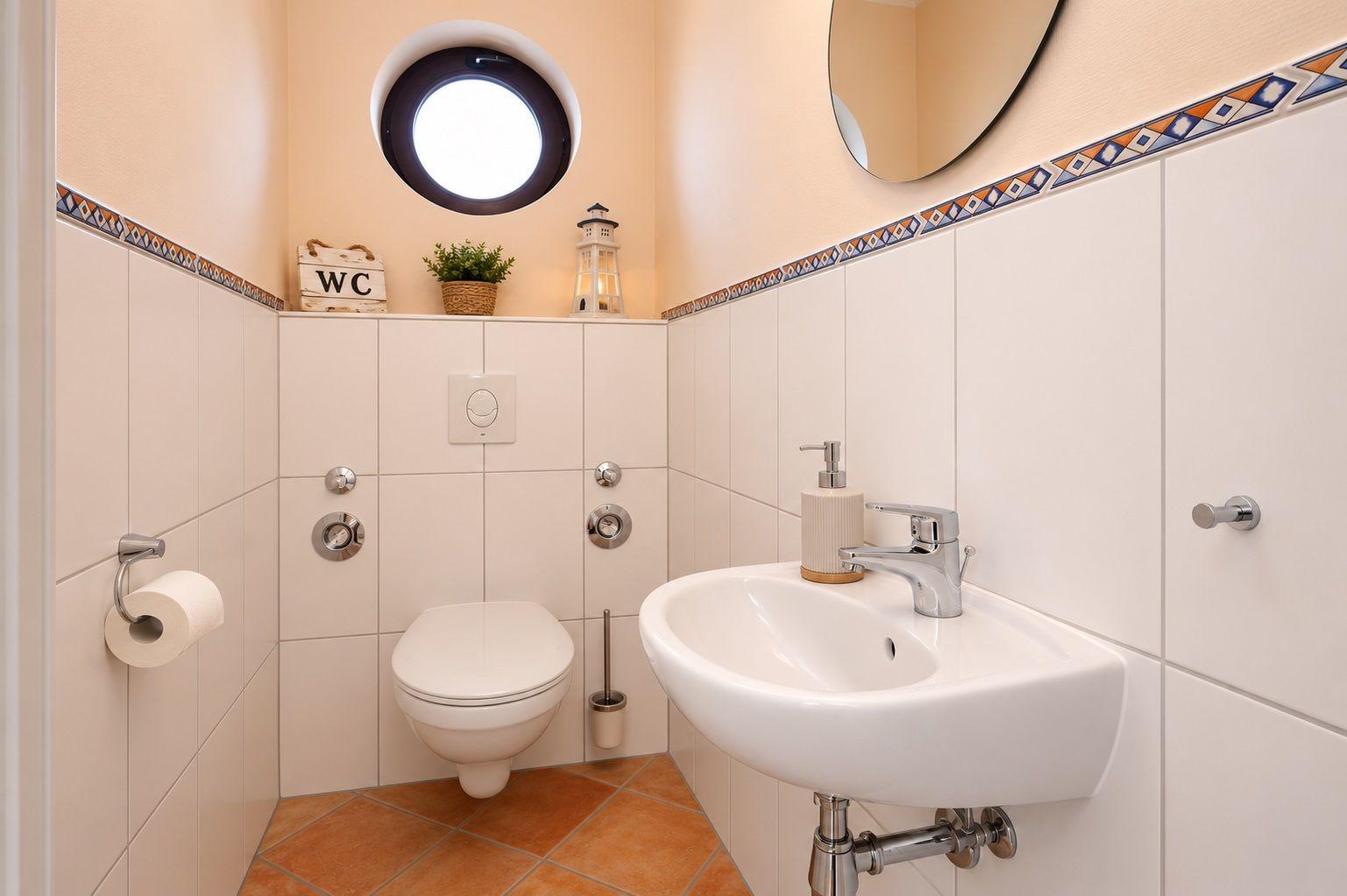 Badezimmer mit Toilette, Waschbecken und runden Fenster