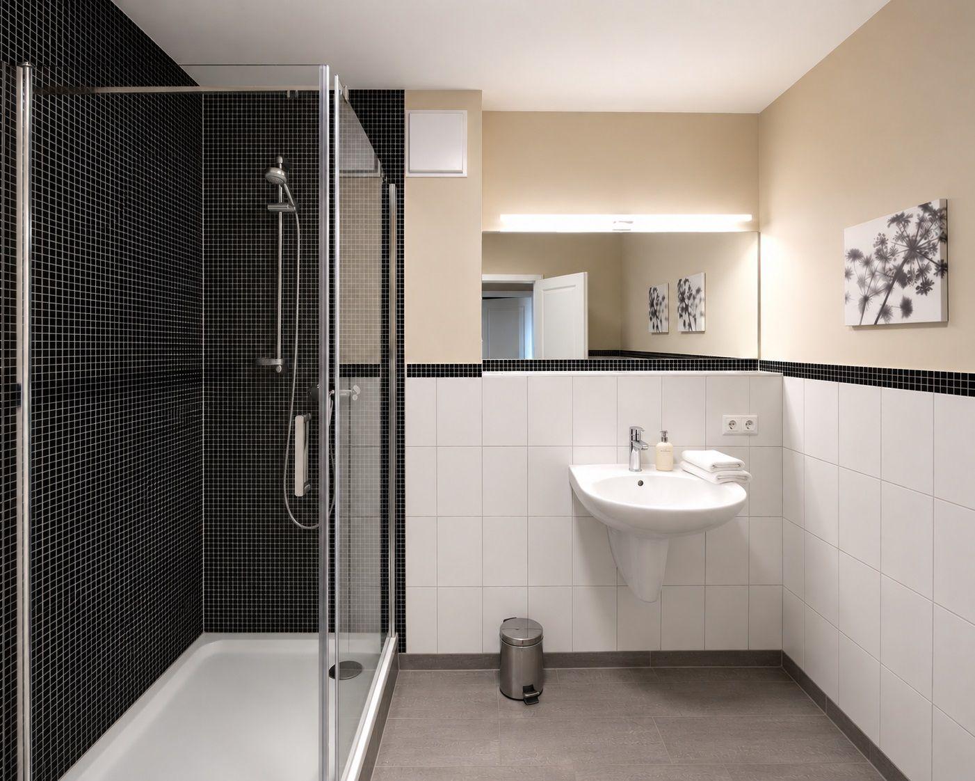Badezimmer mit Dusche, Waschbecken und Spiegel.