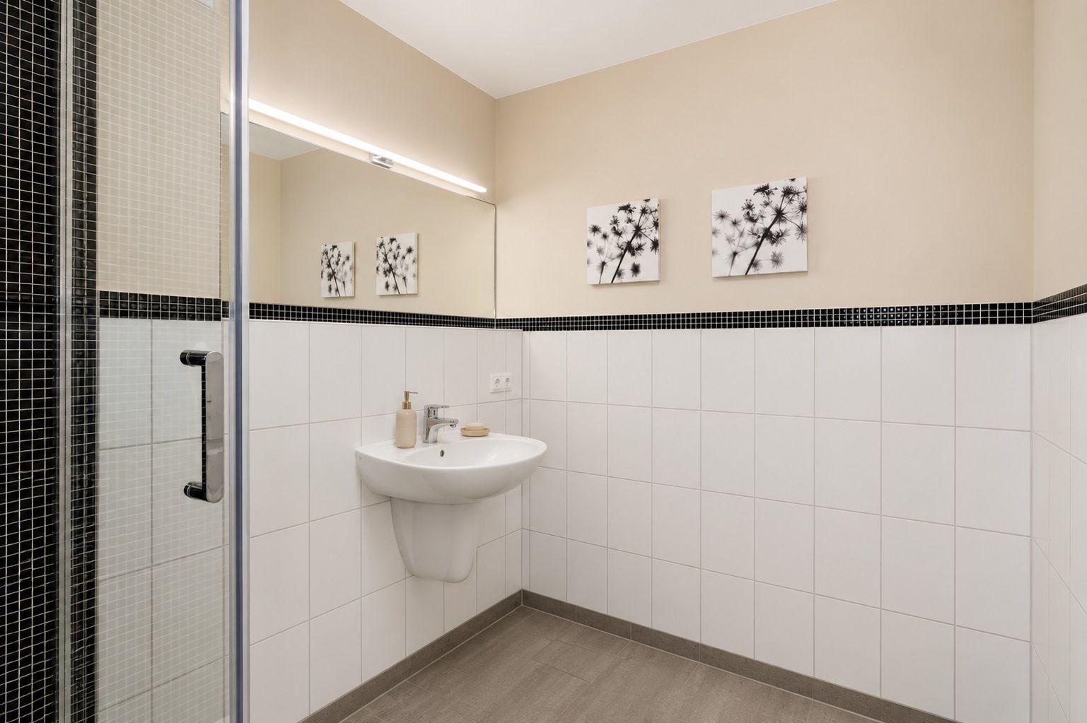 Badezimmer mit Dusche, Handtuchhalter und Waschbecken.