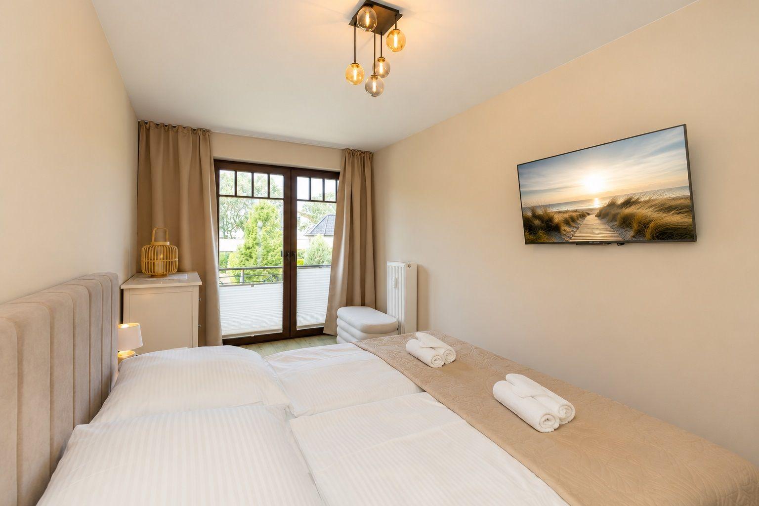 Schlafzimmer mit Doppelbett, TV und Balkonansicht.