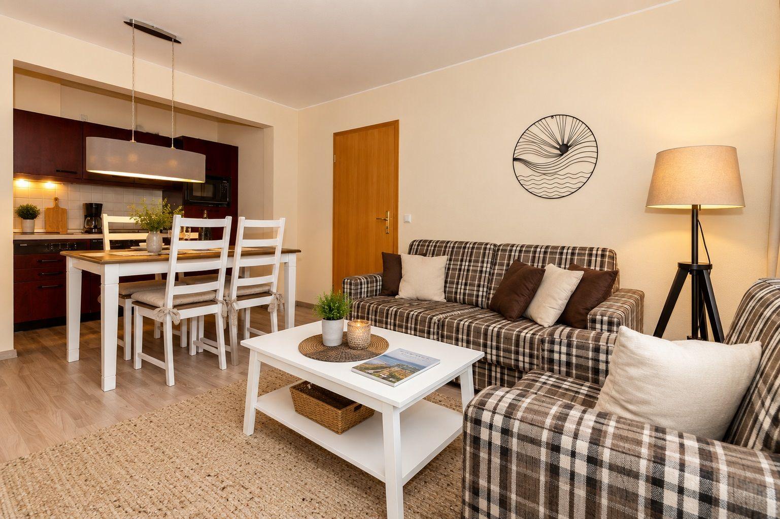 Living and dining area with plaid sofa, dining table, and kitchen area.