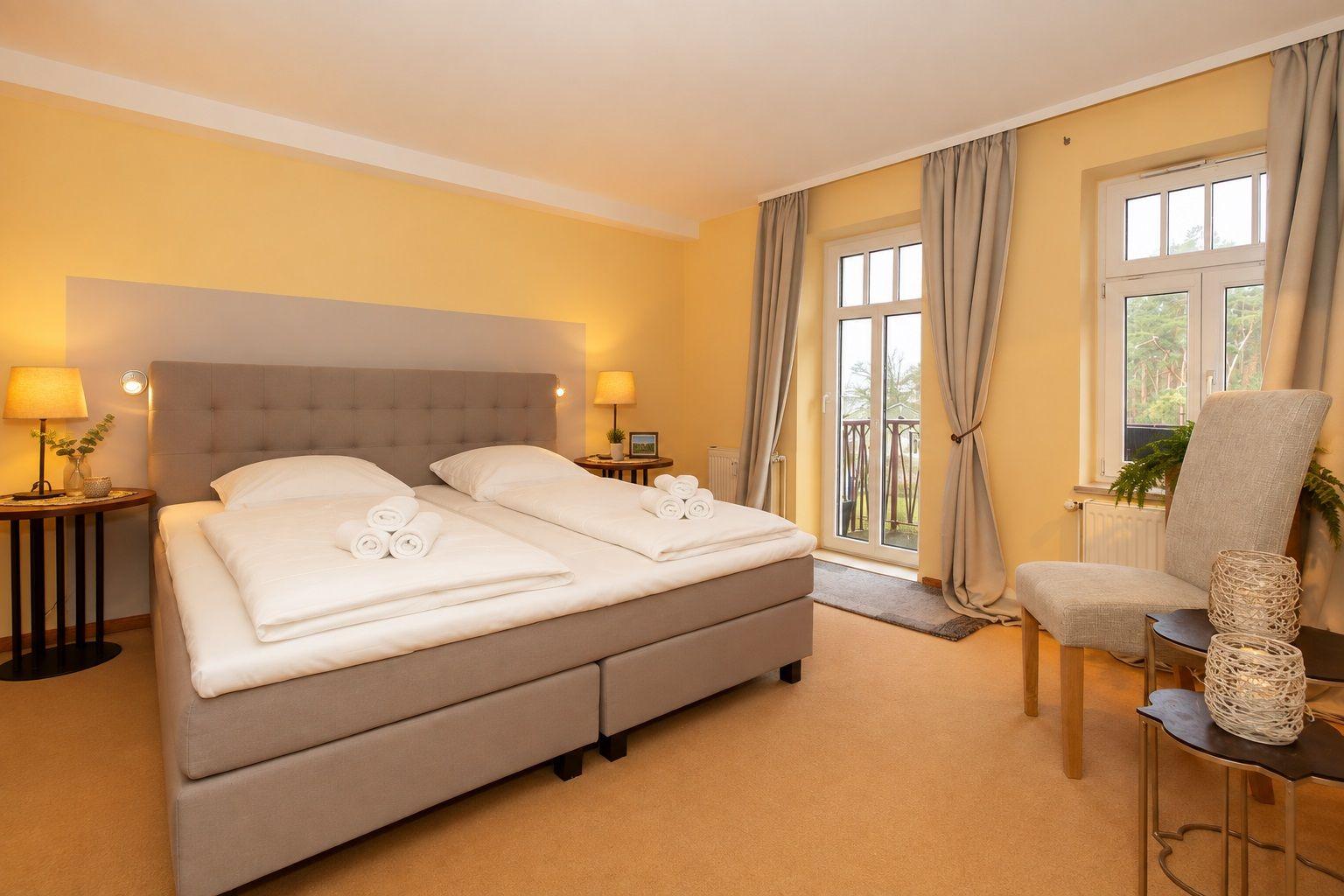 Bedroom with double bed, windows, and seating area.