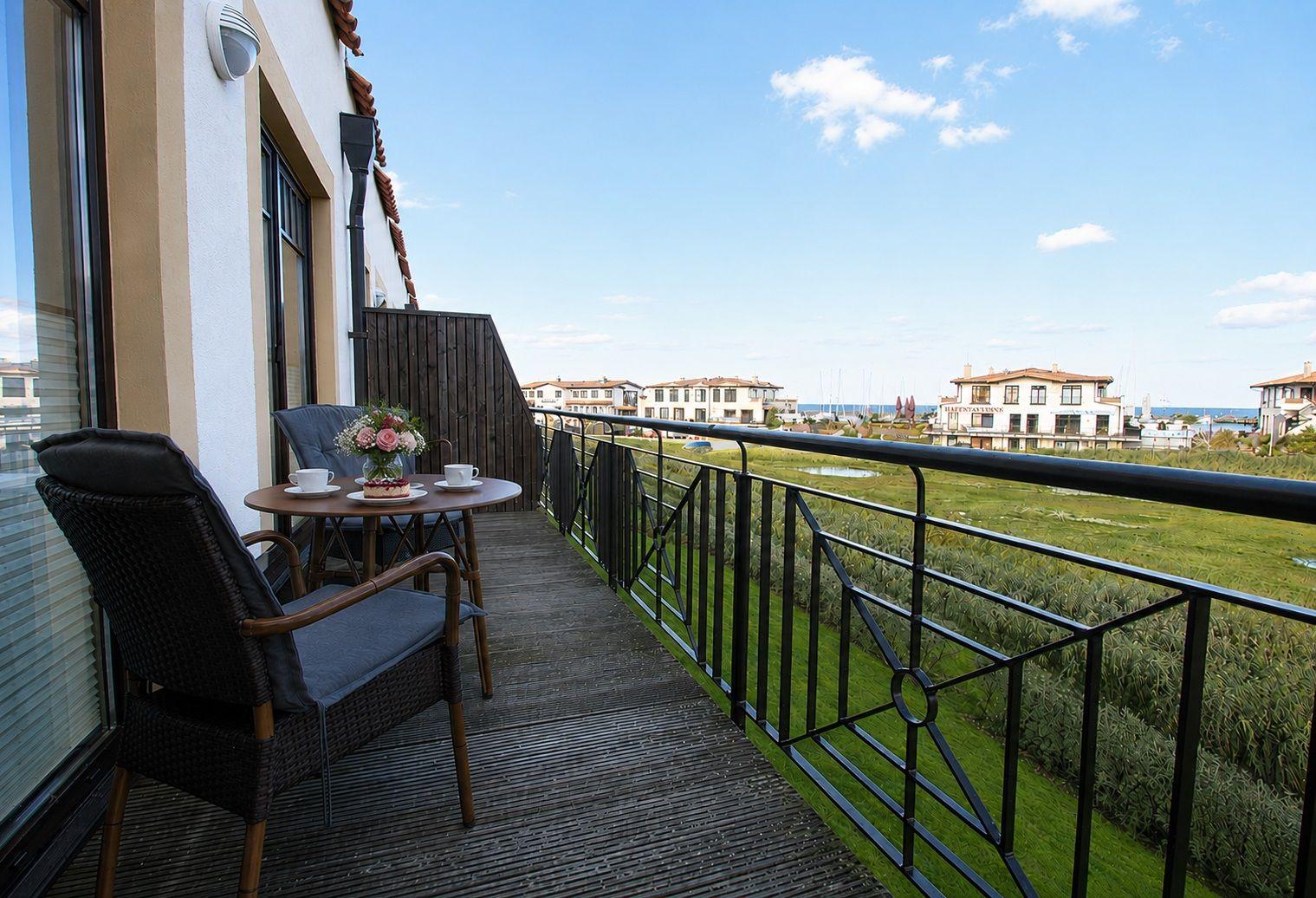 Terrasse mit Tisch und Stühlen, Blick auf Hafen und Gebäude