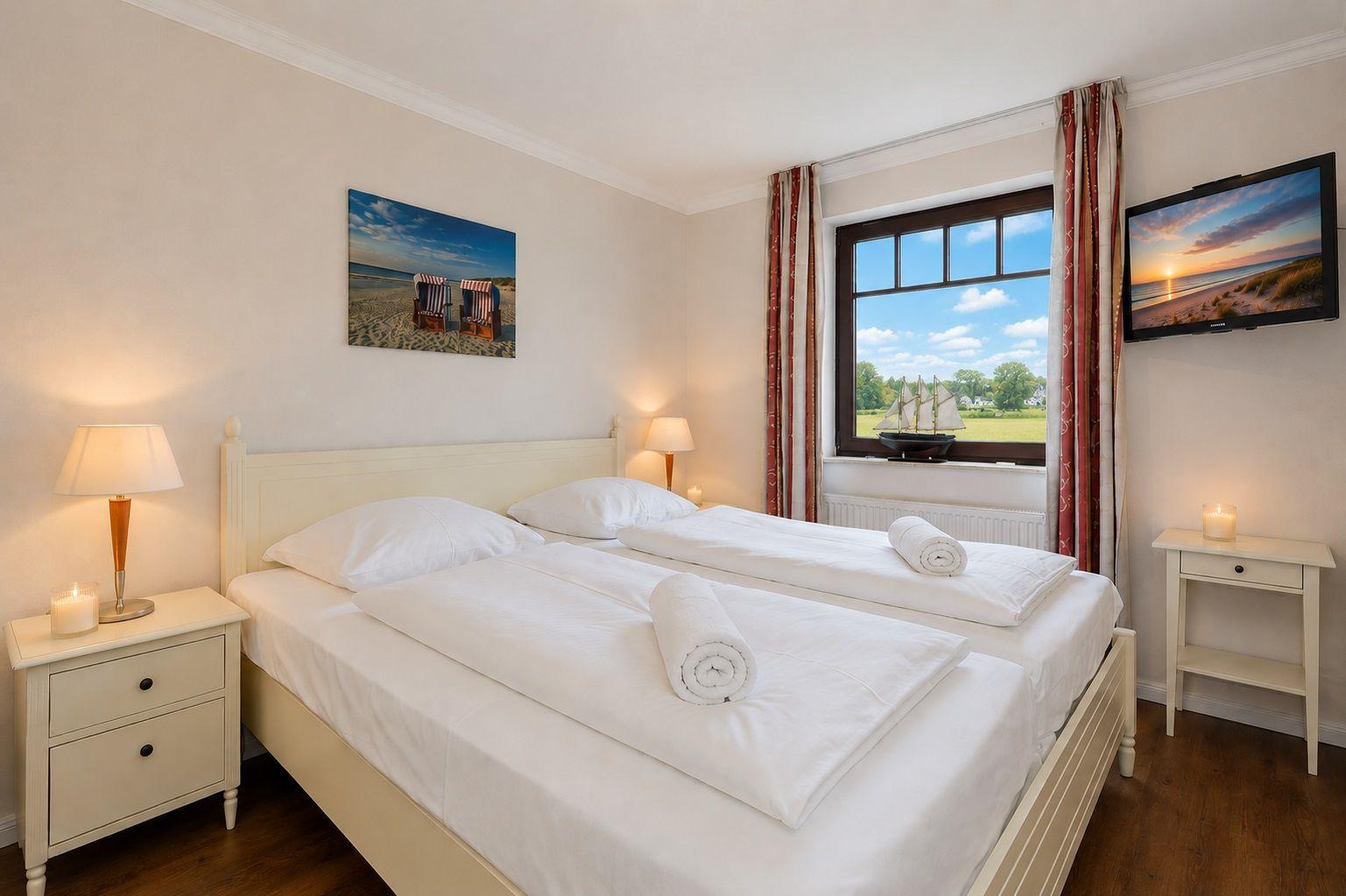 Schlafzimmer mit Doppelbett, Nachttischen und Kleiderschrank. Wandbild zeigt Strandstühle.