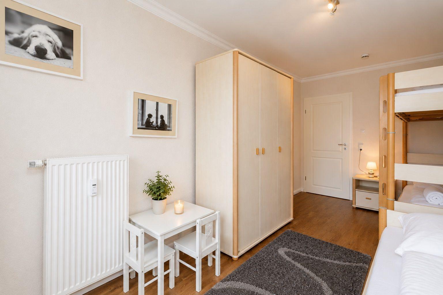 Schlafzimmer mit Doppelstockbett, Kleiderschrank und Nachttisch.
