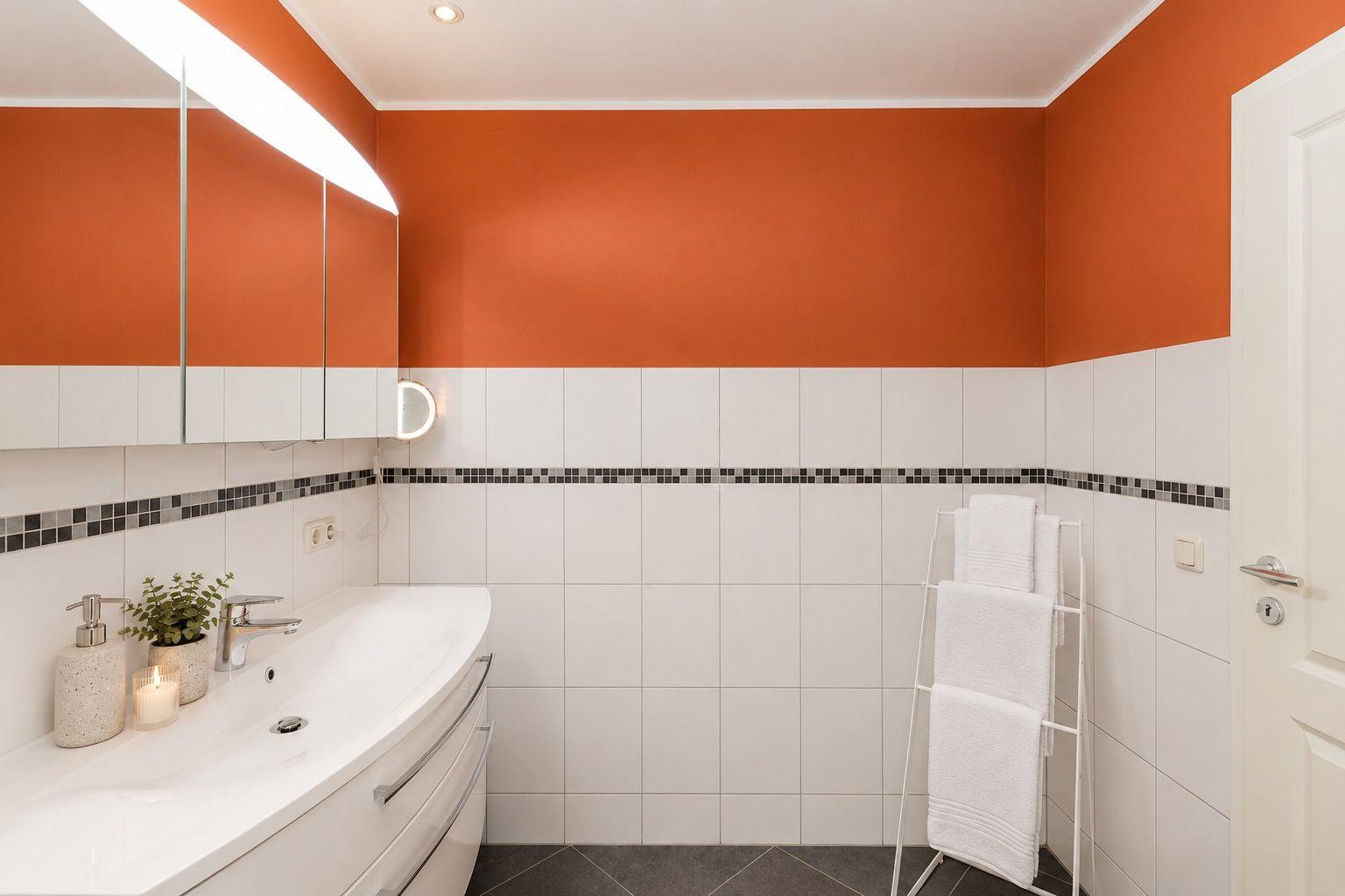 Badezimmer mit Dusche, Waschbecken und Heizkörper an orangefarbenen Wänden.