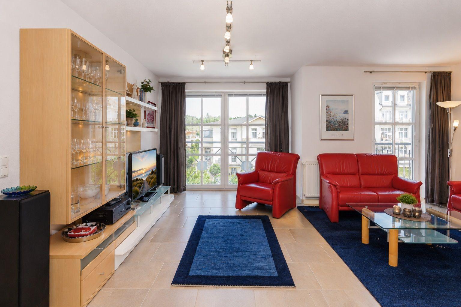 Wohnzimmer mit rotem Sofa, Glaswand und TV-Möbel