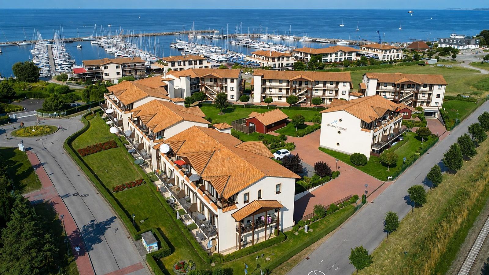 Hochwertige Ferienwohnungen mit Balkonen direkt am Hafen. Blick auf das Wasser und viele Segelboote.