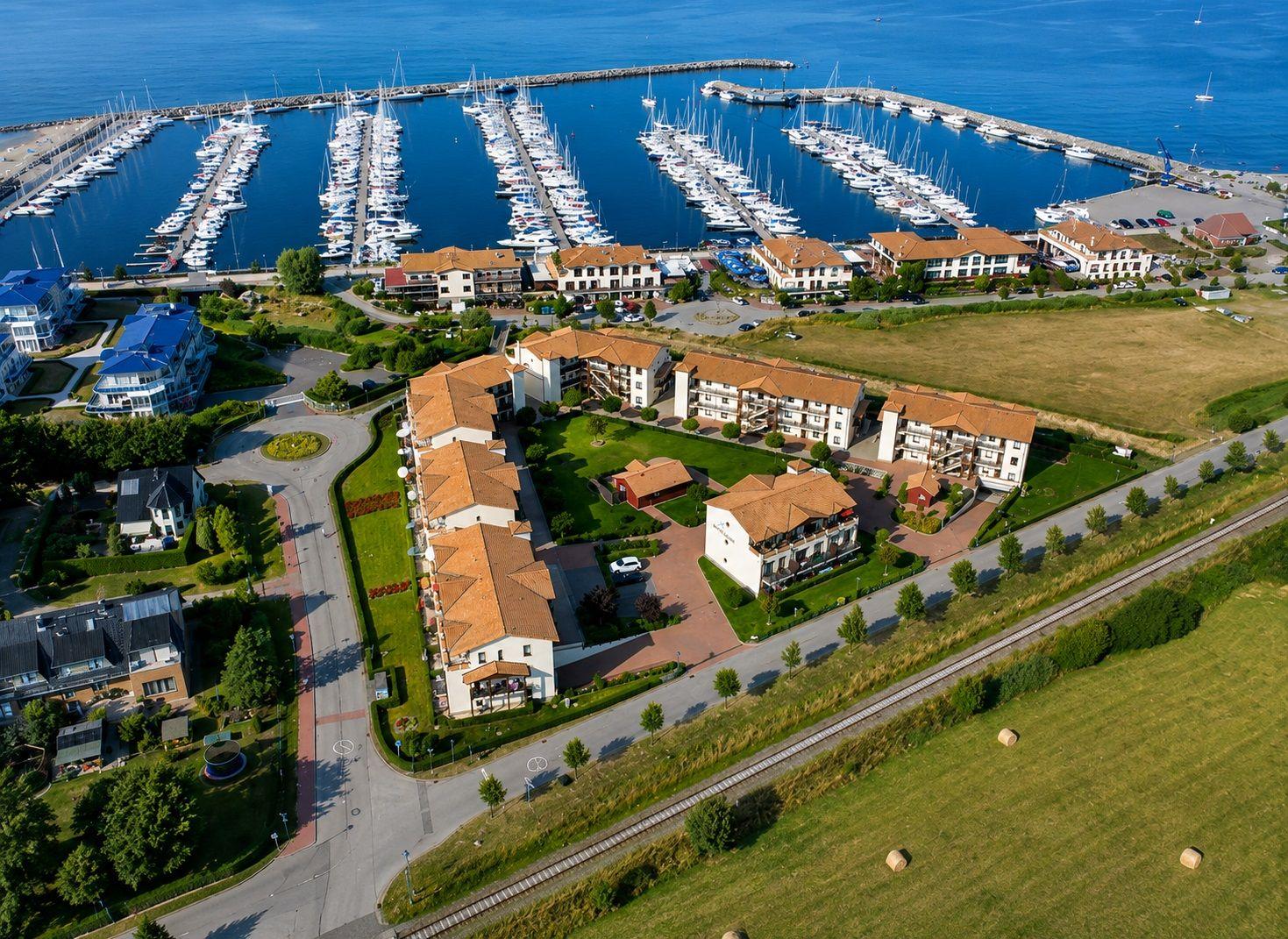 Aerial view of a marina with boats and surrounding residential buildings near the water.