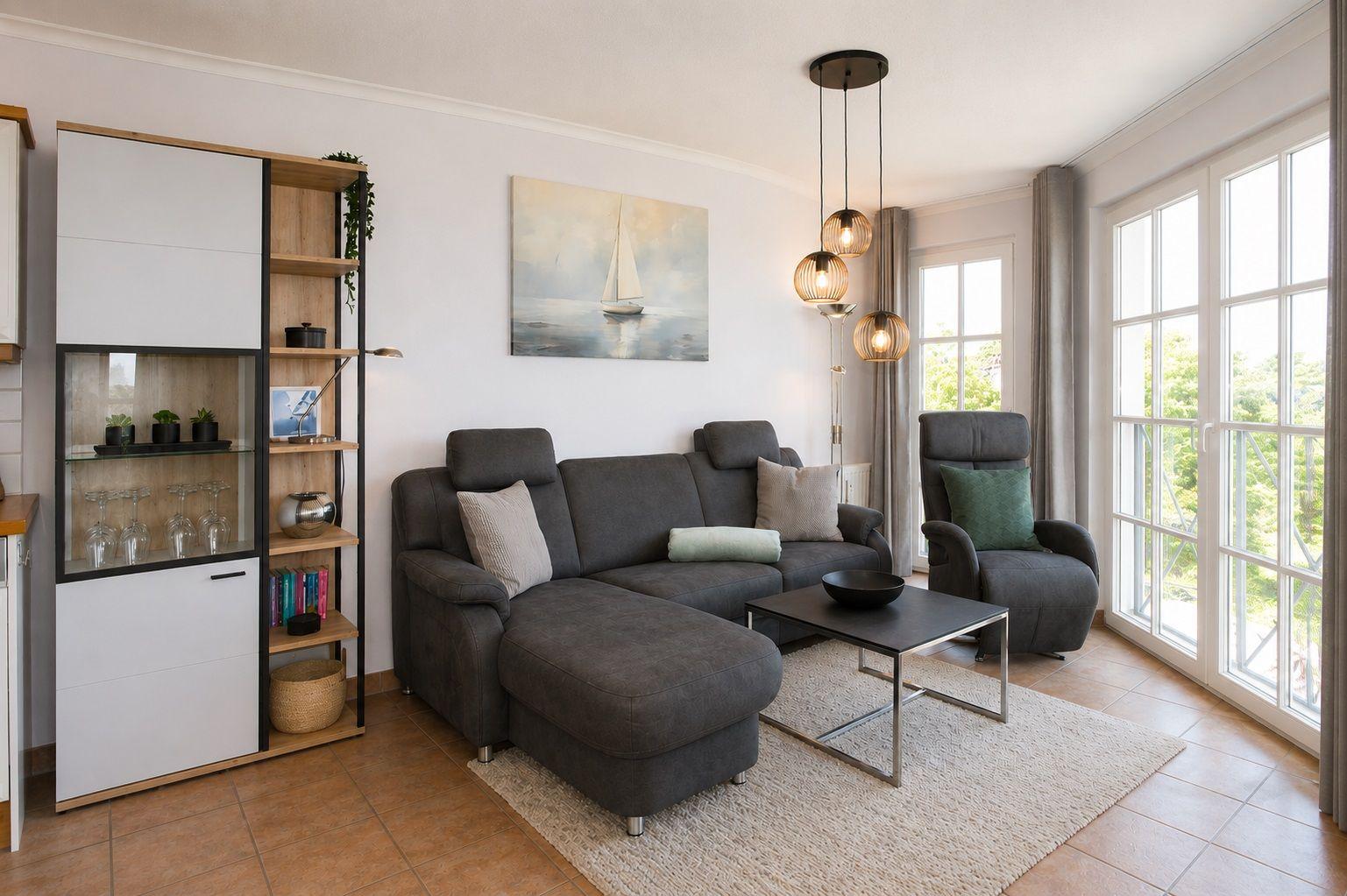 Wohnzimmer mit Sofa, Fernseher und Meerblick durch große Fenster.