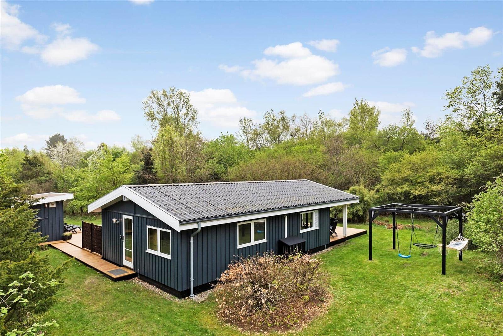 Backyard with sandbox, garden bench, and play kitchen under trees.