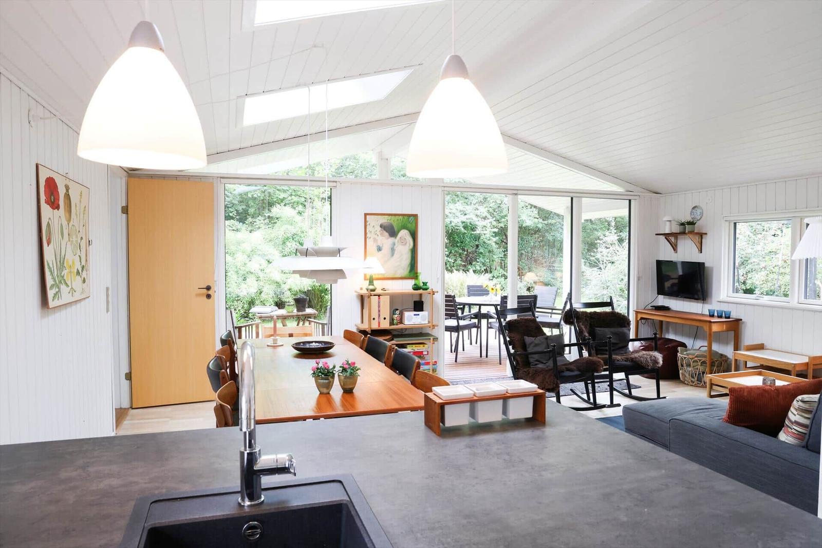 Dining room with wooden table, six chairs, and wall art. Two pendant lamps over the table.