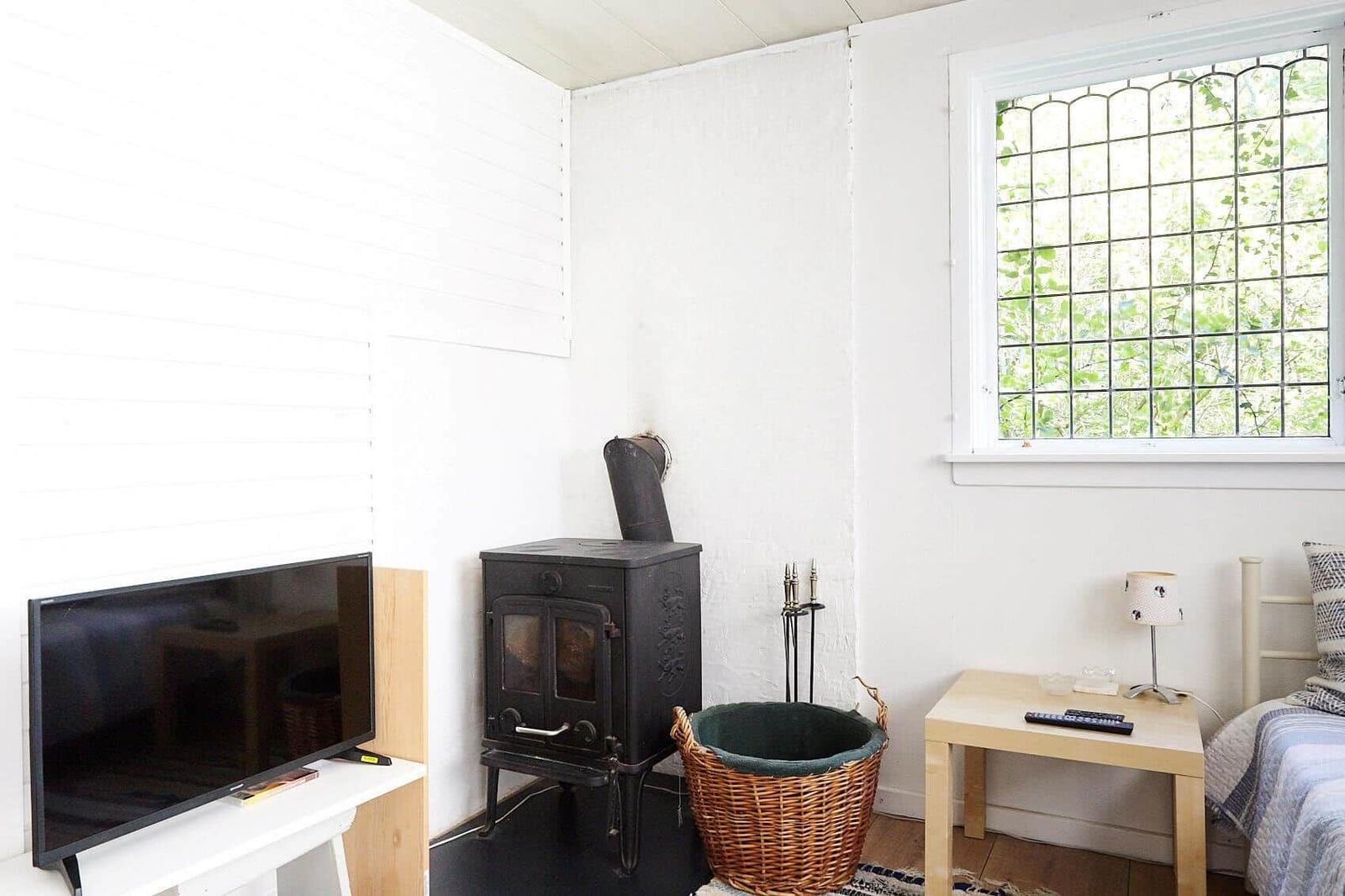 Black wooden house with white door and garden area with picnic table.