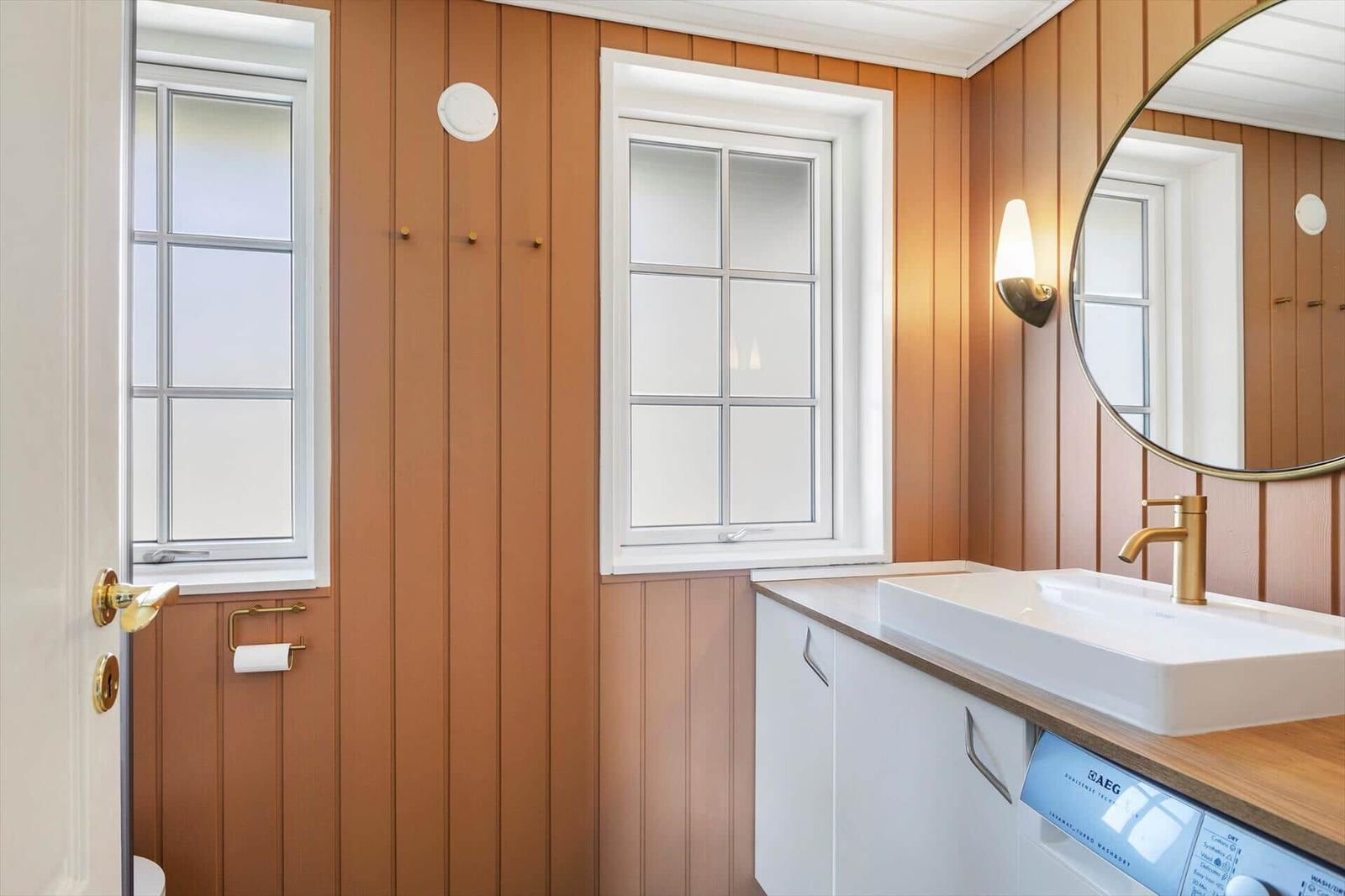 Badezimmer mit Holzwand, Waschbecken und Spiegel