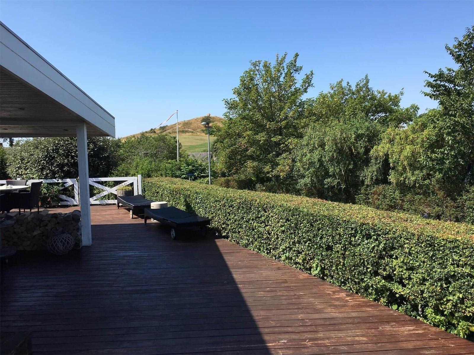 Deck with view of sea and green areas through large sliding glass doors.