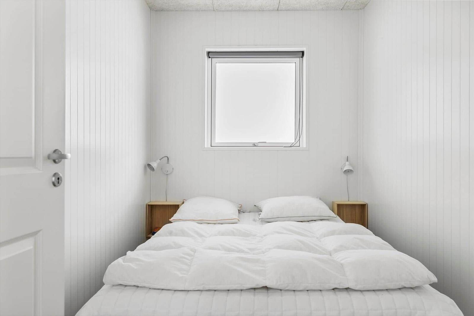 Ein Bett mit grünem Bettbezug in einem weißen Nischenbett mit zwei Wandlampen.