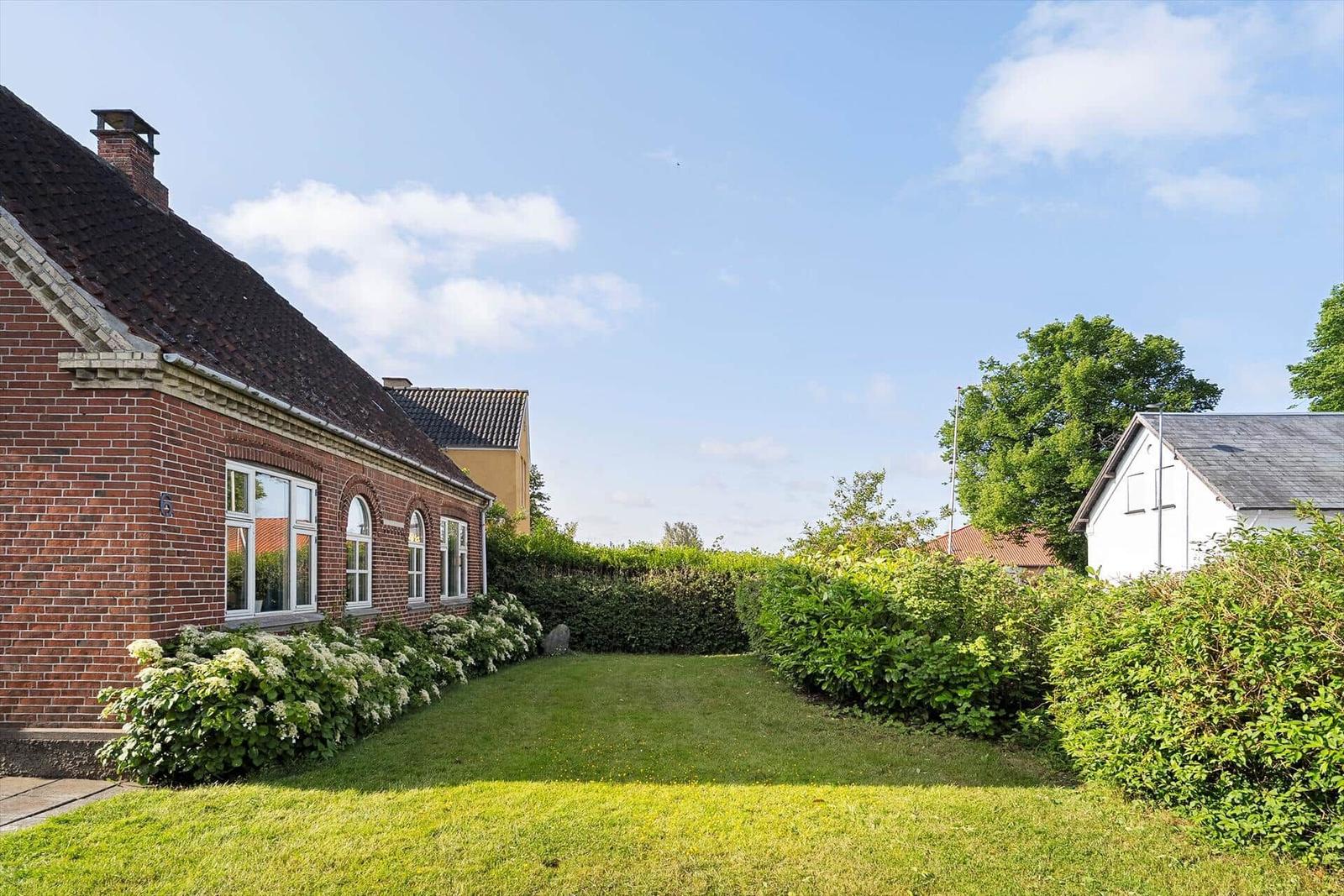 Red brick house with terrace, garden, and sun loungers. Passage to bedroom.