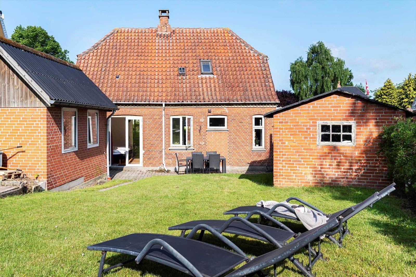White chapel with red roof, bicycles and stroller near a lake.