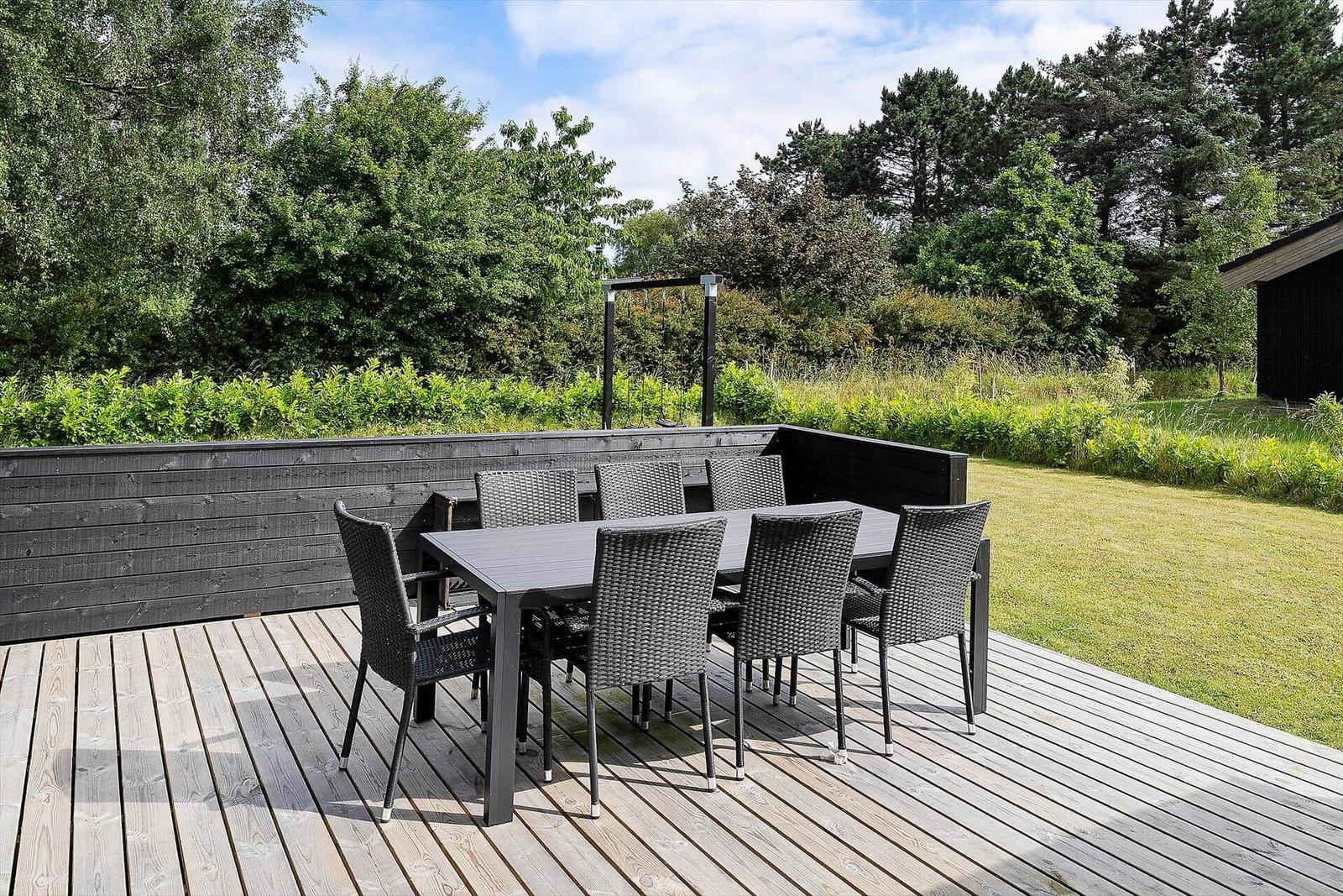 Modern wooden cabin with large terrace area and garden.