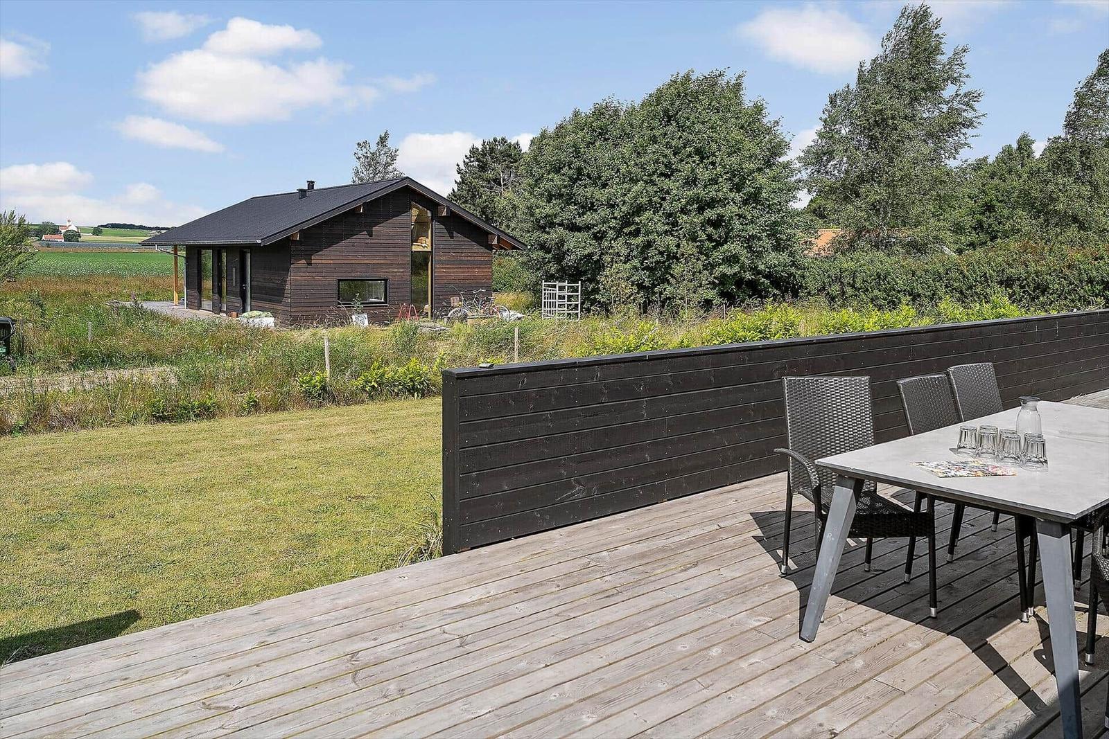 Deck with table, chairs, and seating. Glass enclosure and wooden floor.