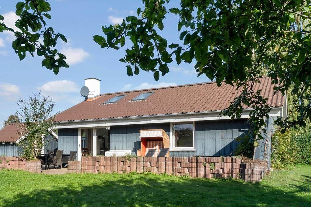 A house with terrace, garden, and skylights under trees.