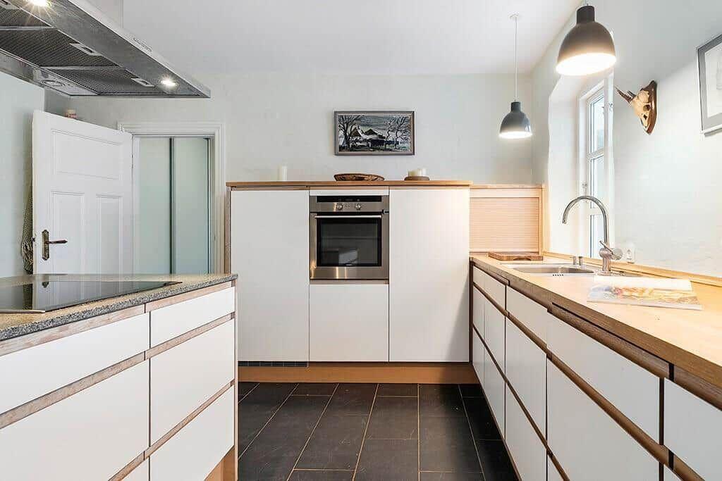 Kitchen with wooden countertop, window, faucet, and wine bottle.