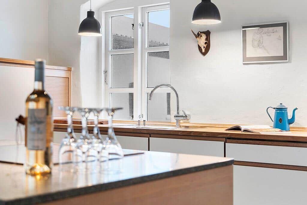 Dining area with table and chairs, kitchen with island and windows.