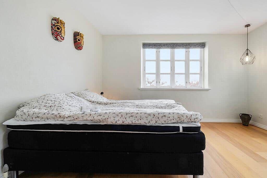 Bedroom with bed, two windows, and hardwood floor.